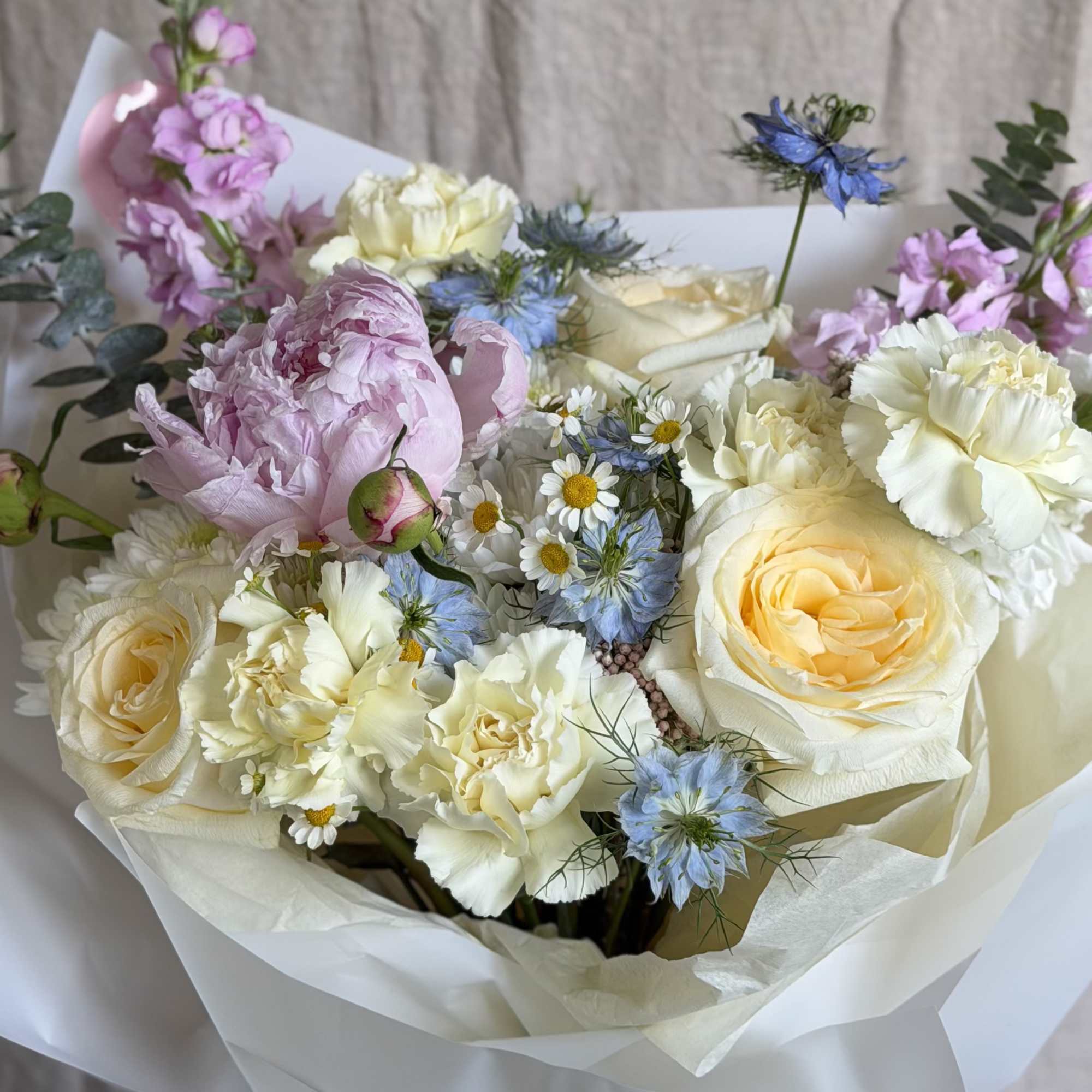 Large blush peonies paired with cream and pale yellow roses create a