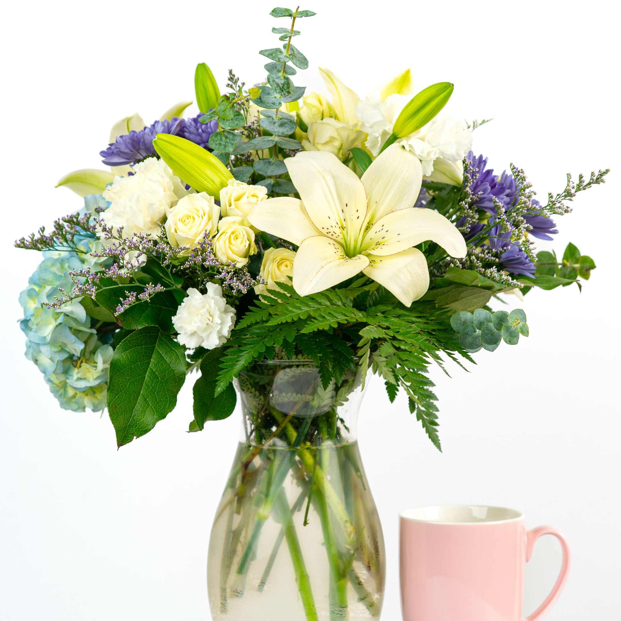 Bouquet of lilies, roses, hydrangea, and purple flowers in a glass vase
