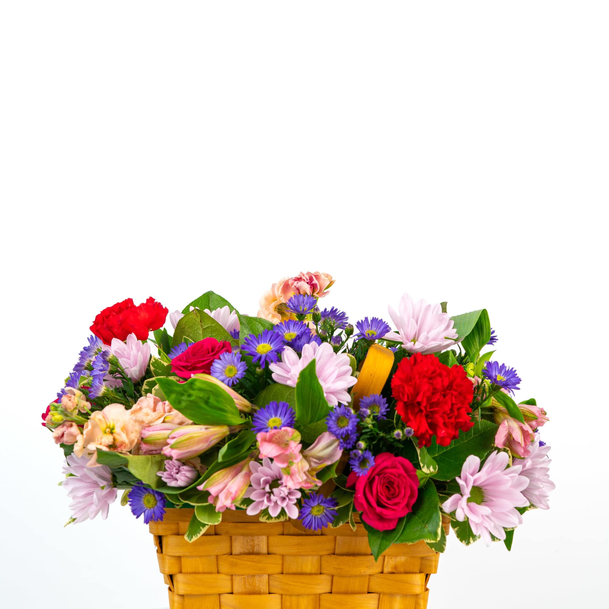 Low basket arrangement of pink daisies, red roses, red carnations, and purple asters in a woven wood basket