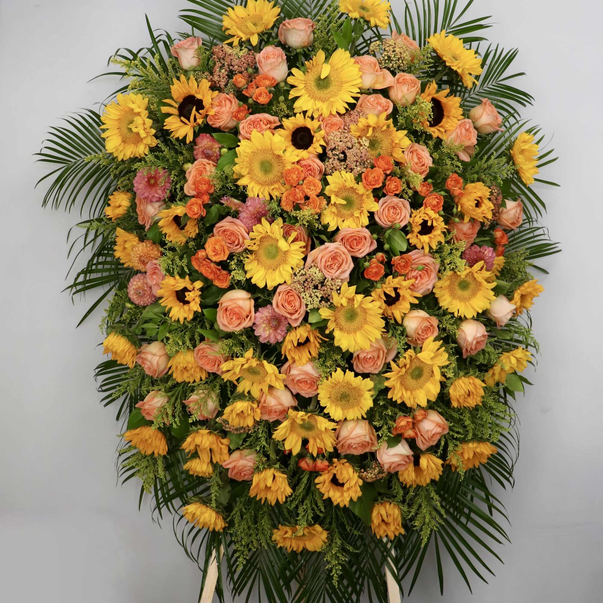 This sympathy spray is made with sunflowers, roses, tulips, calla lilies, and