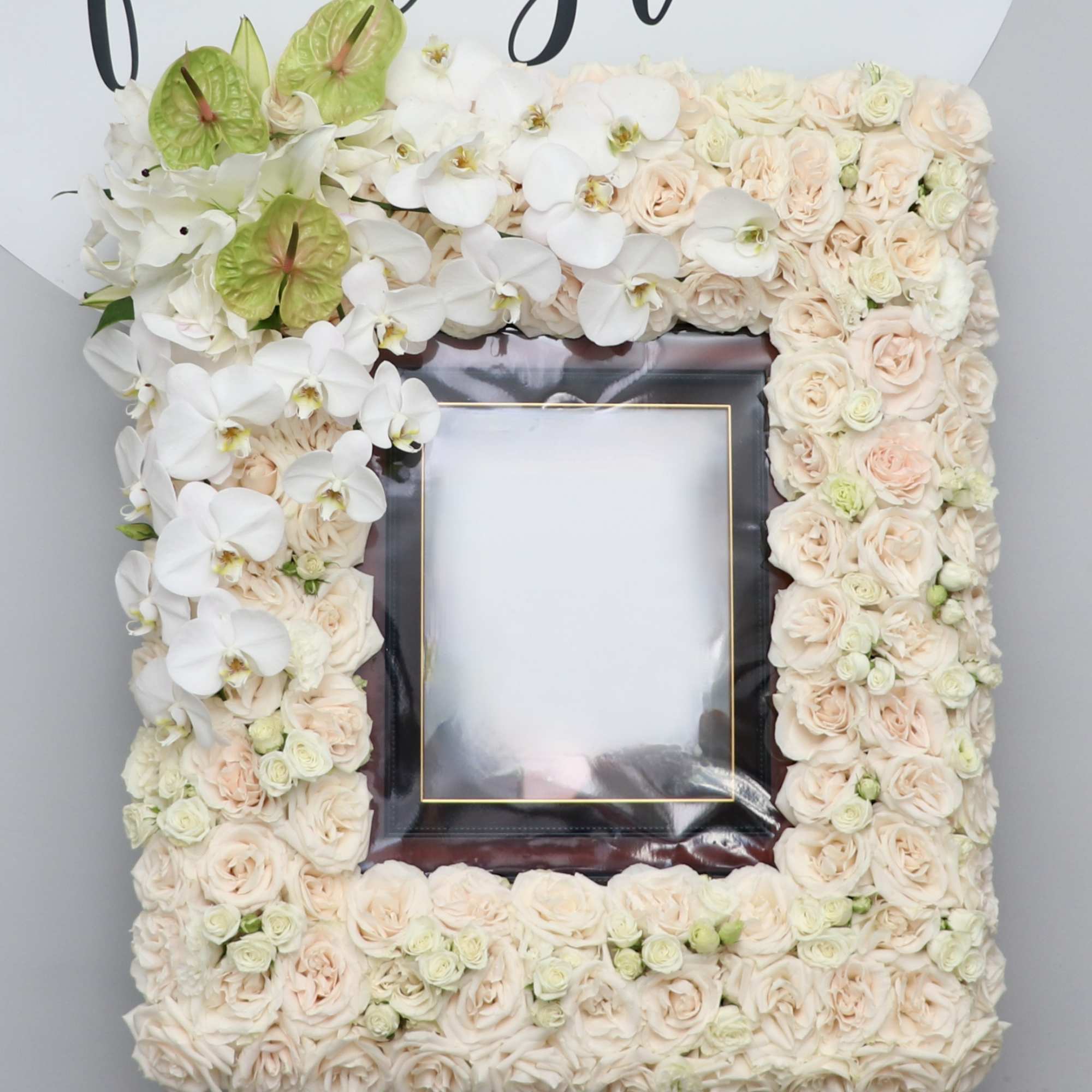 Floral frame of pale roses and white orchids around a photo opening