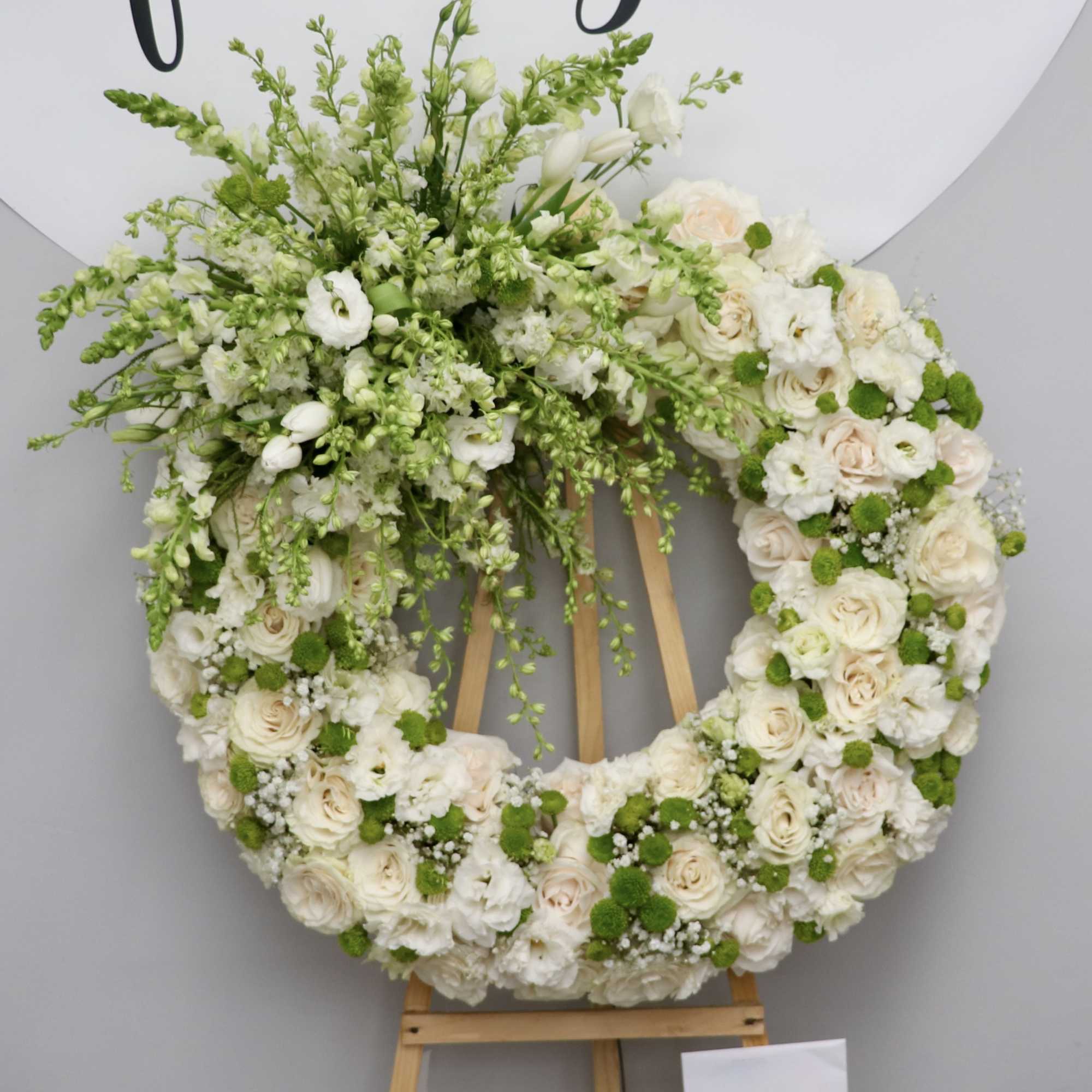 Large white floral wreath on a wooden easel