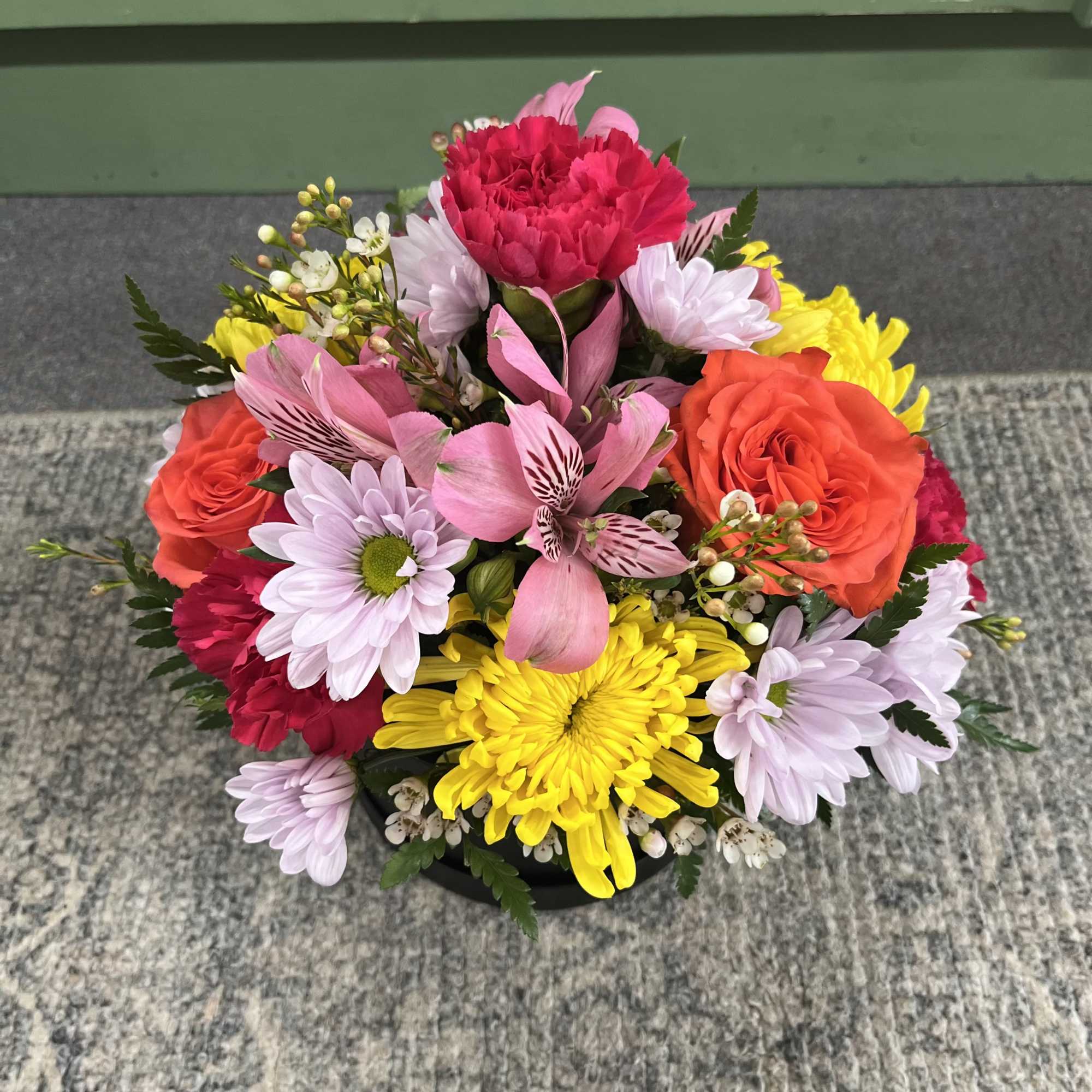 This arrangement combines cheerful yellow chrysanthemums with pink alstroemeria, soft lavender daisies