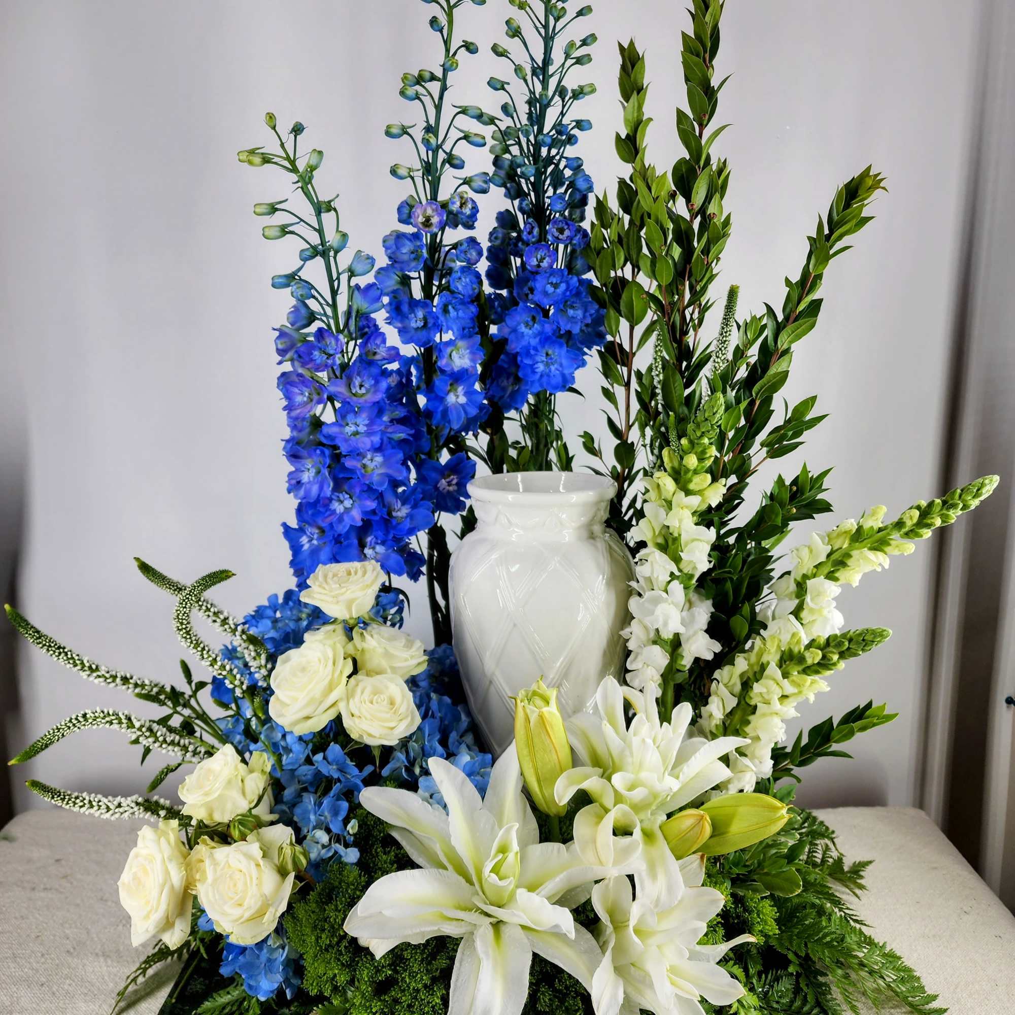 Tall floral arrangement with blue and white flowers in a white vase