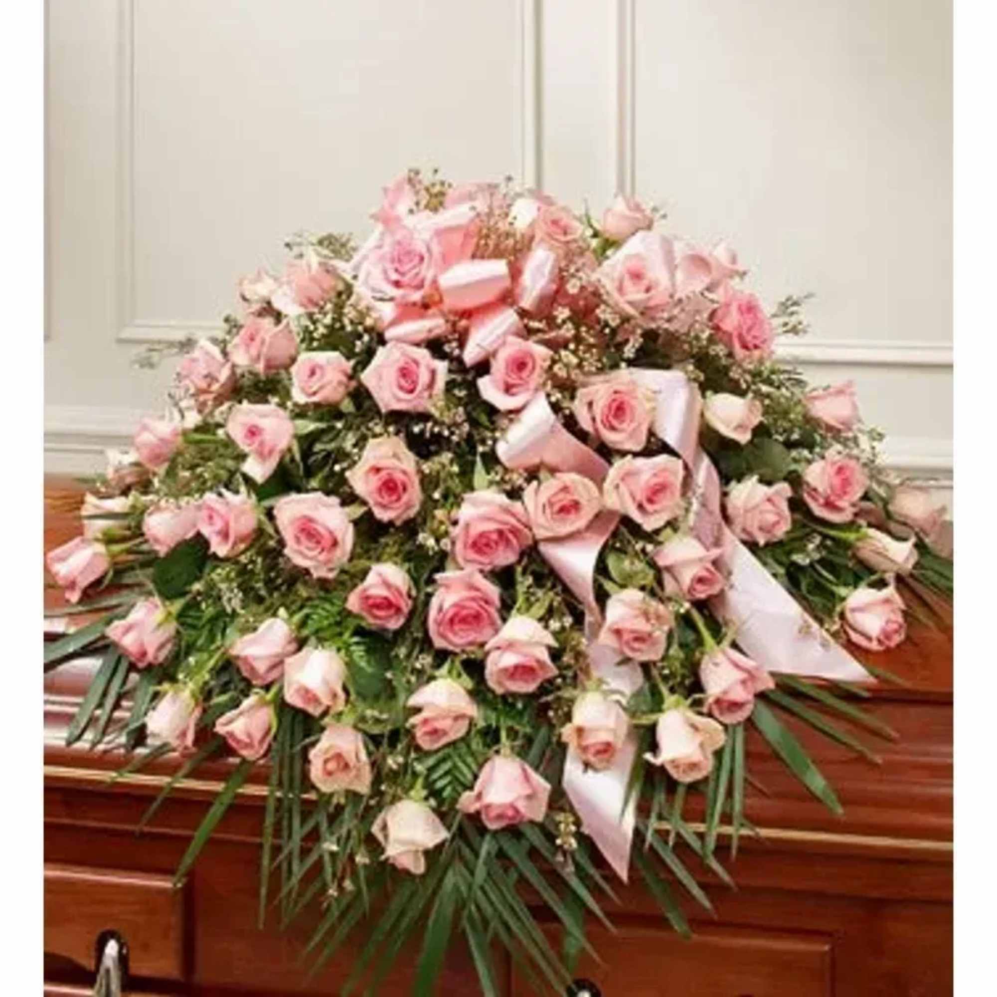 Pale pink roses arranged in a large, cascading casket spray create a