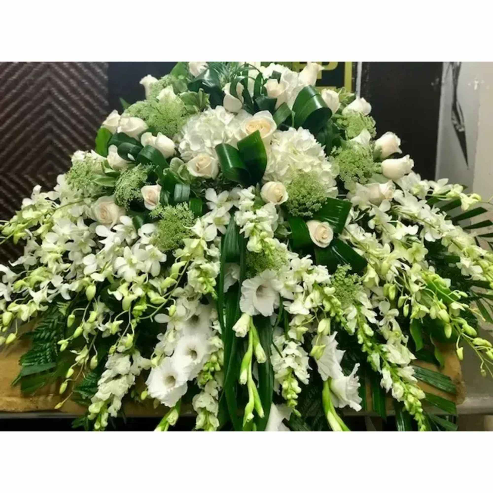 A sweeping cascade of white roses, orchids and rounded hydrangea clusters that