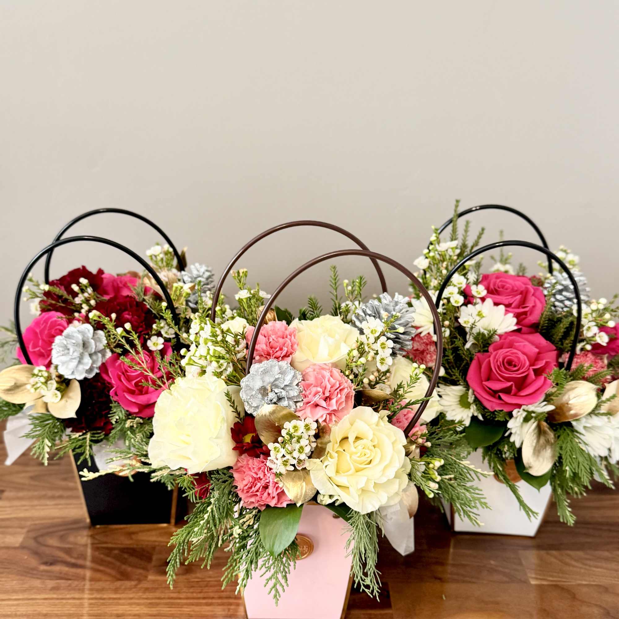 Three floral arrangements in pastel boxes with roses and carnations