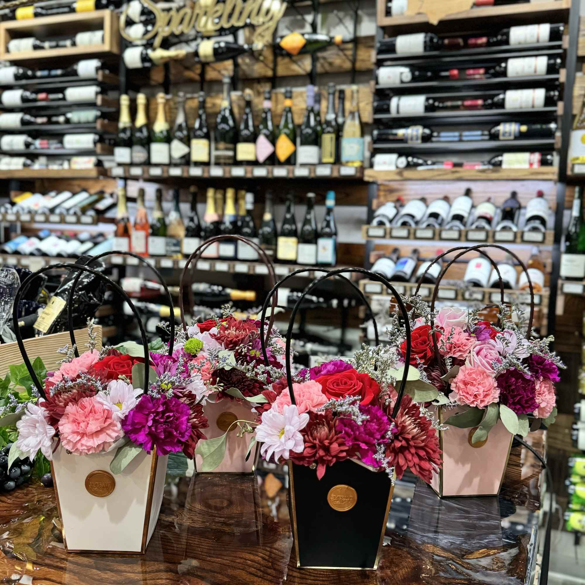 Three flower baskets with pink, red, and white blooms on a table