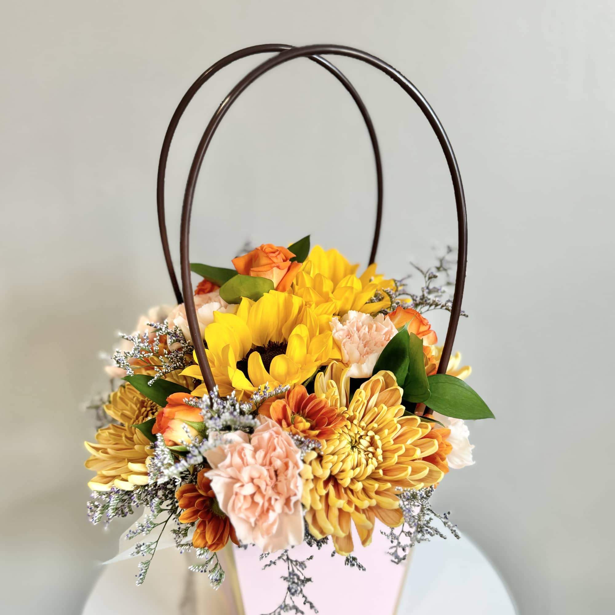 Basket arrangement of yellow and peach flowers with arched handles