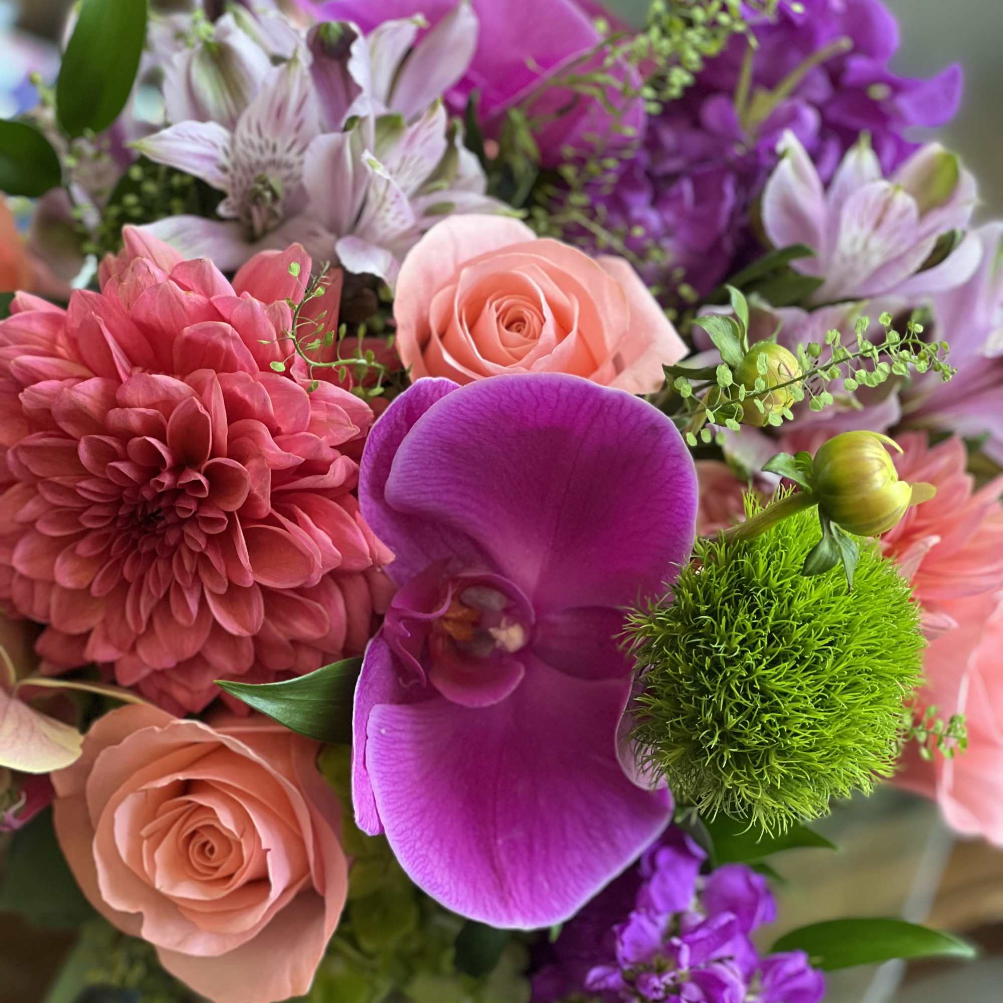 Bouquet of pink, purple, and peach flowers with a bright green pom-pom bloom