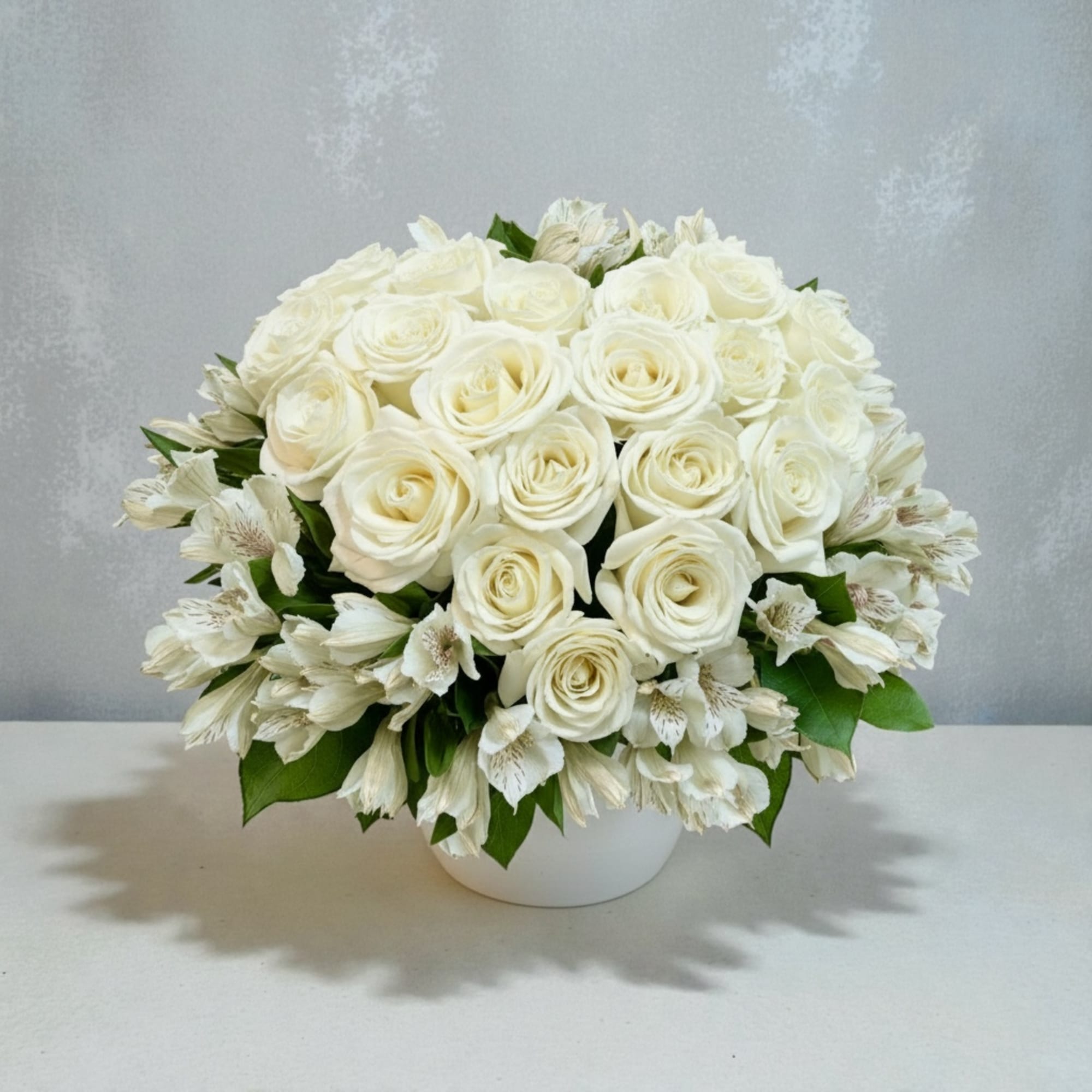 White rose bouquet with small white flowers in a white vase