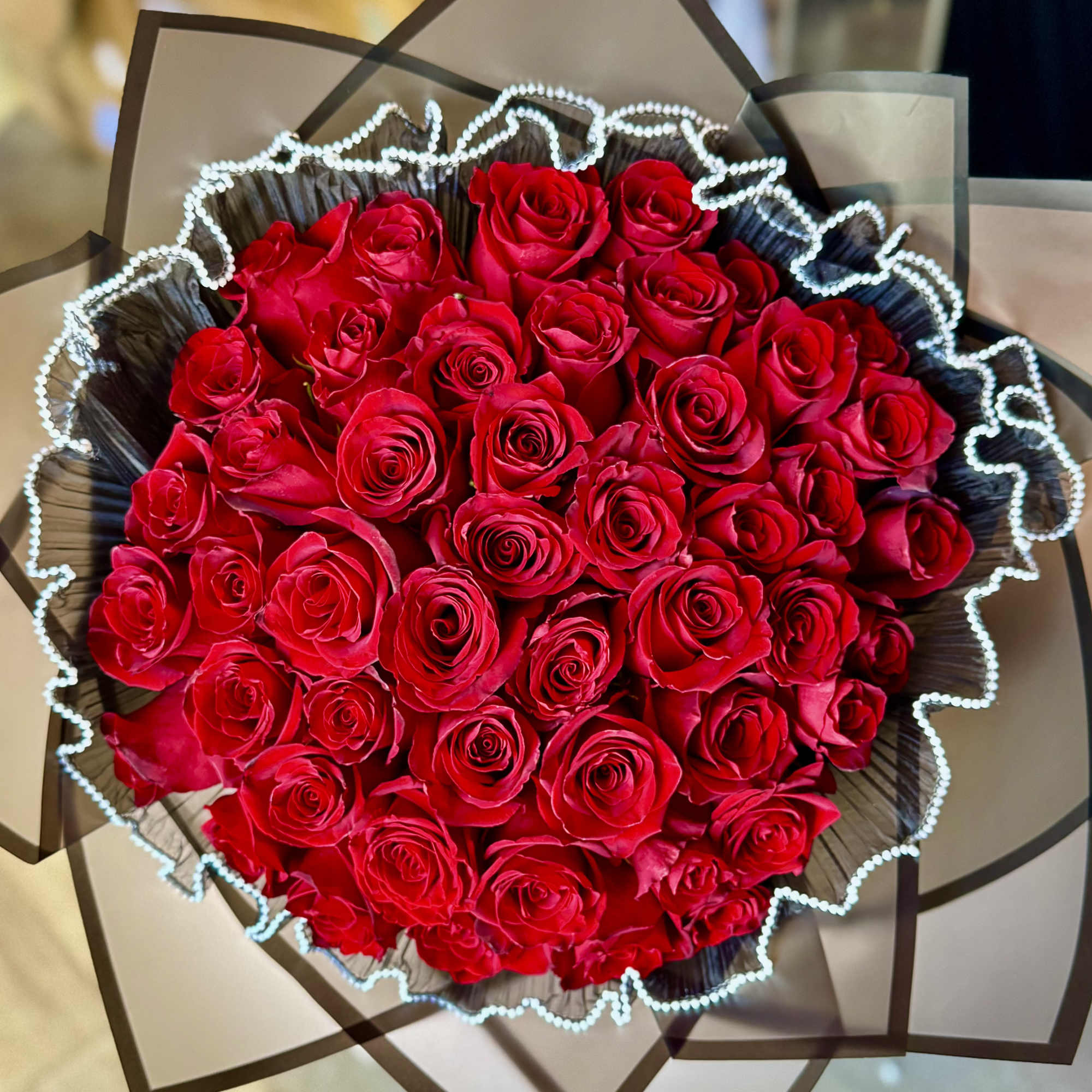 Large bouquet of red roses wrapped in dark paper