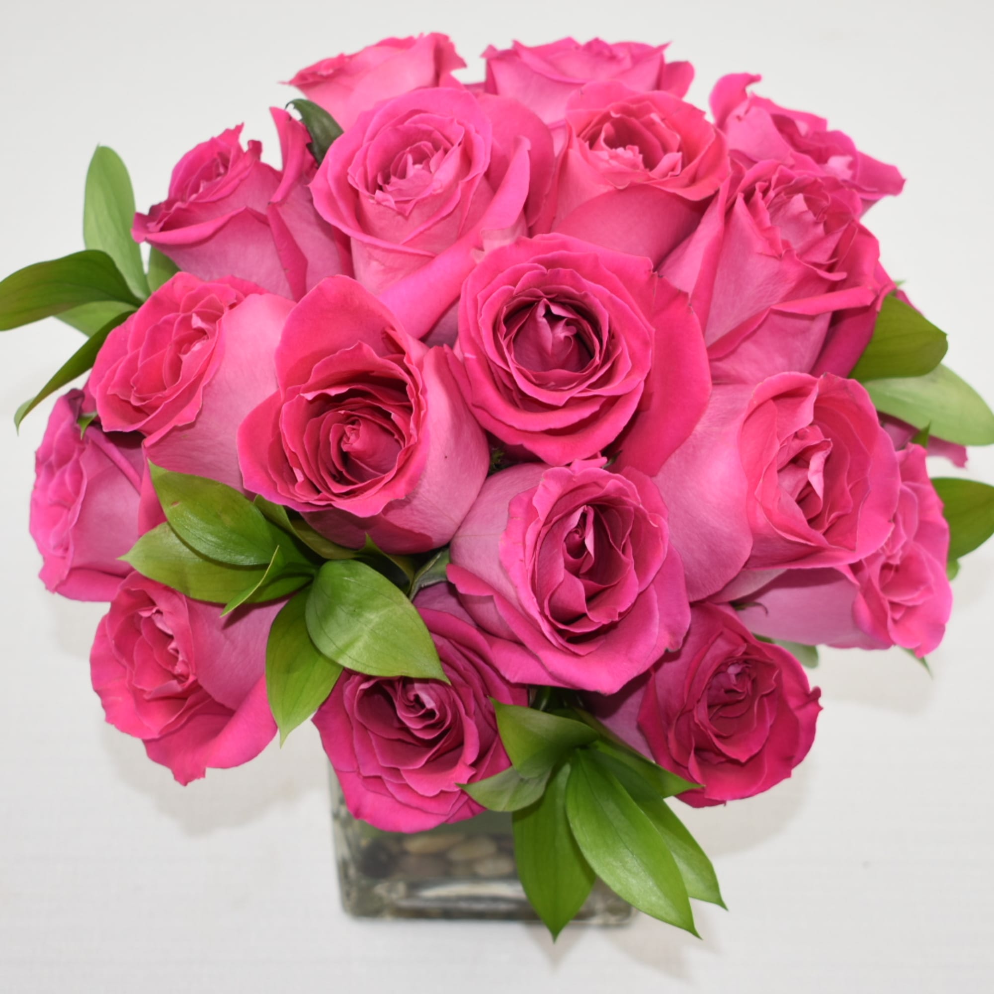 Bouquet of bright pink roses in a clear square vase
