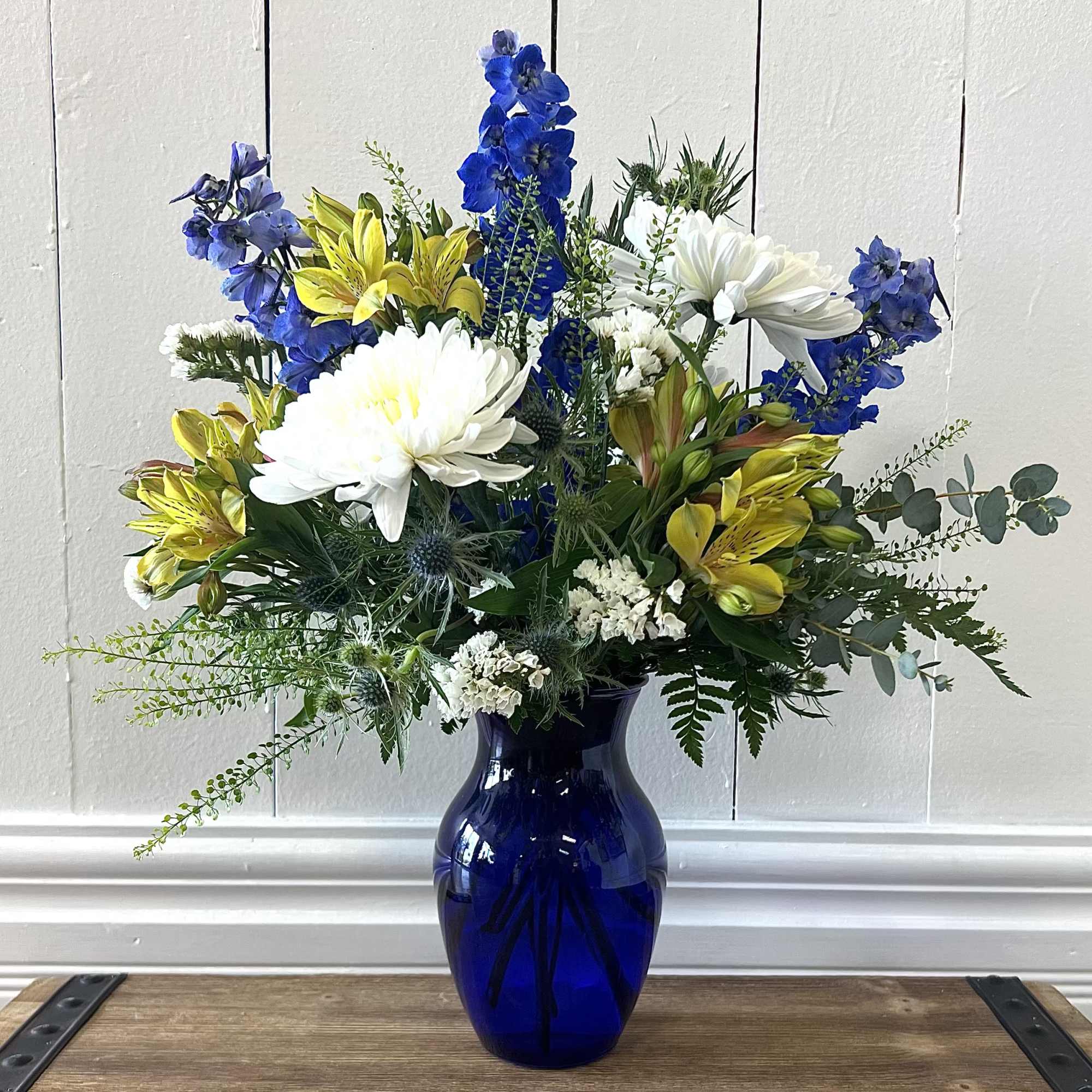A fresh, cheerful mix of blue, white, and yellow blooms arranged in