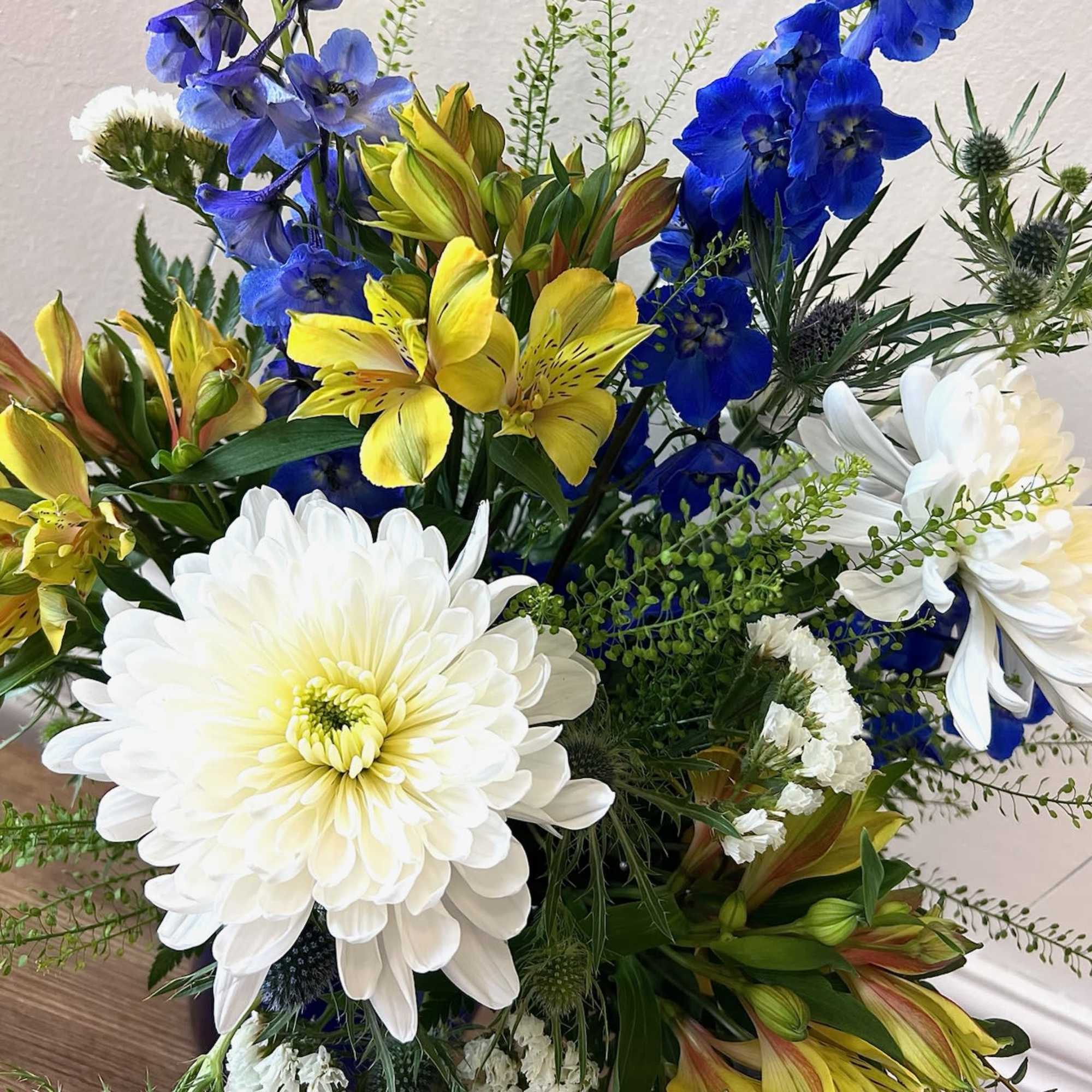 A fresh, cheerful mix of blue, white, and yellow blooms arranged in