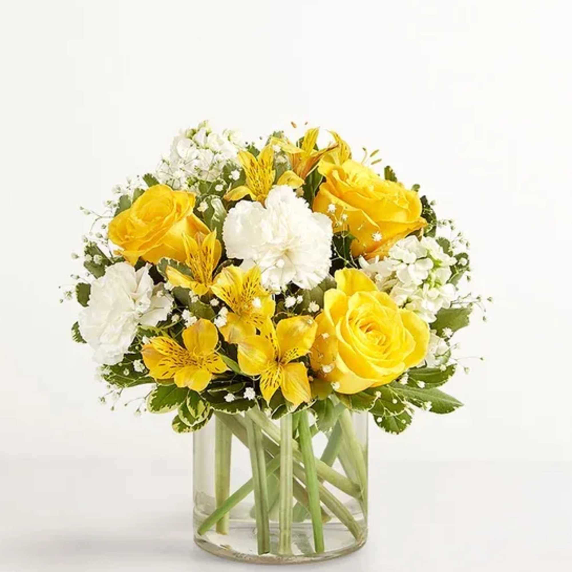 Yellow roses and white flowers arranged in a clear glass vase