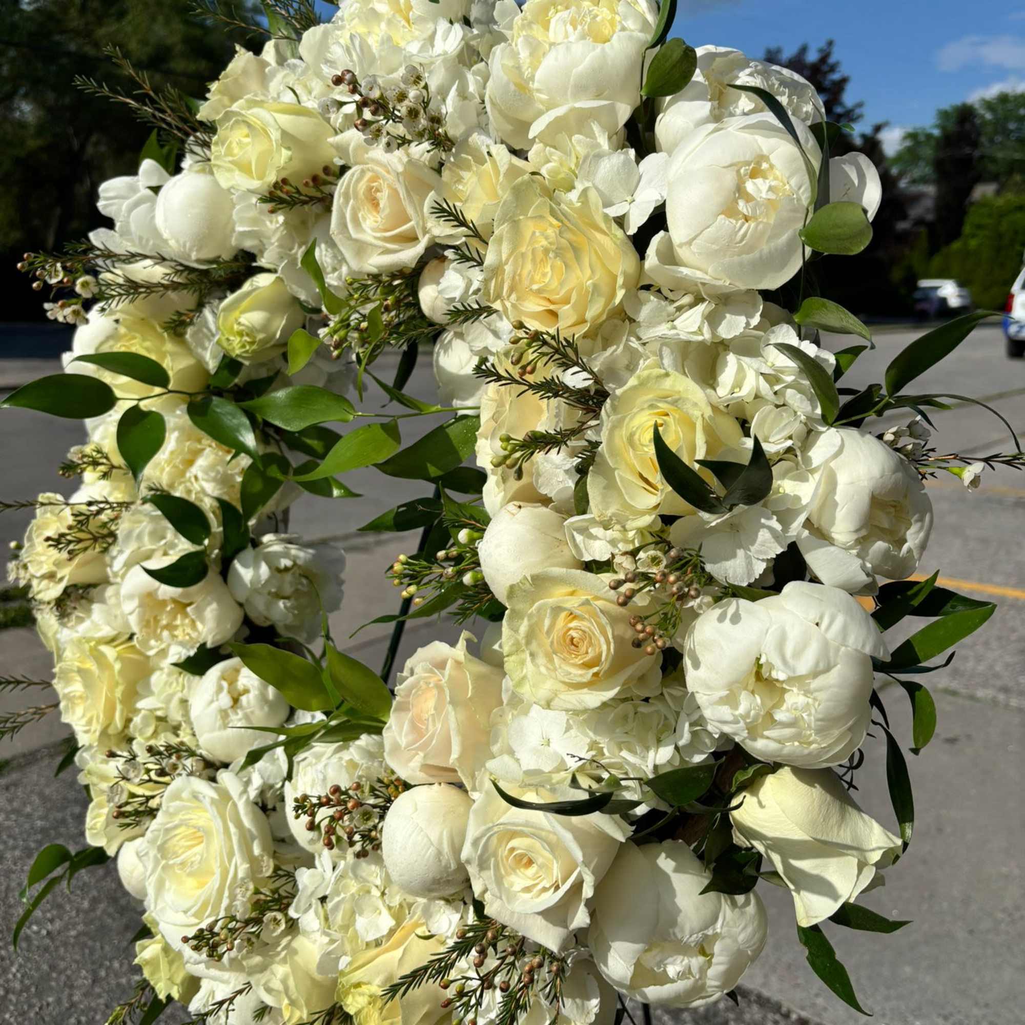 A textured standing wreath featuring of creamy whites and soft pale yellows.