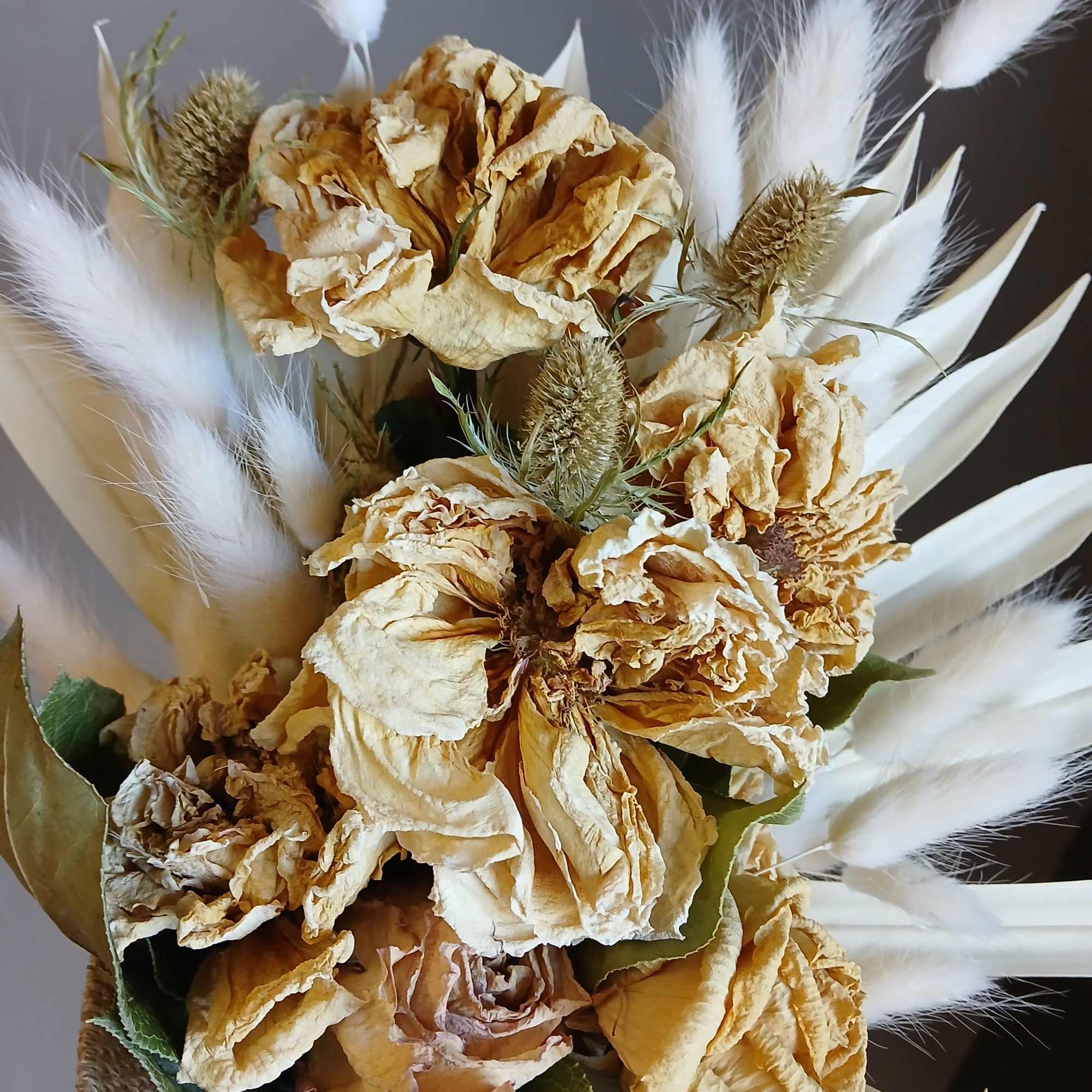Dried beige roses with white accents and pampas grass, wrapped in burlap