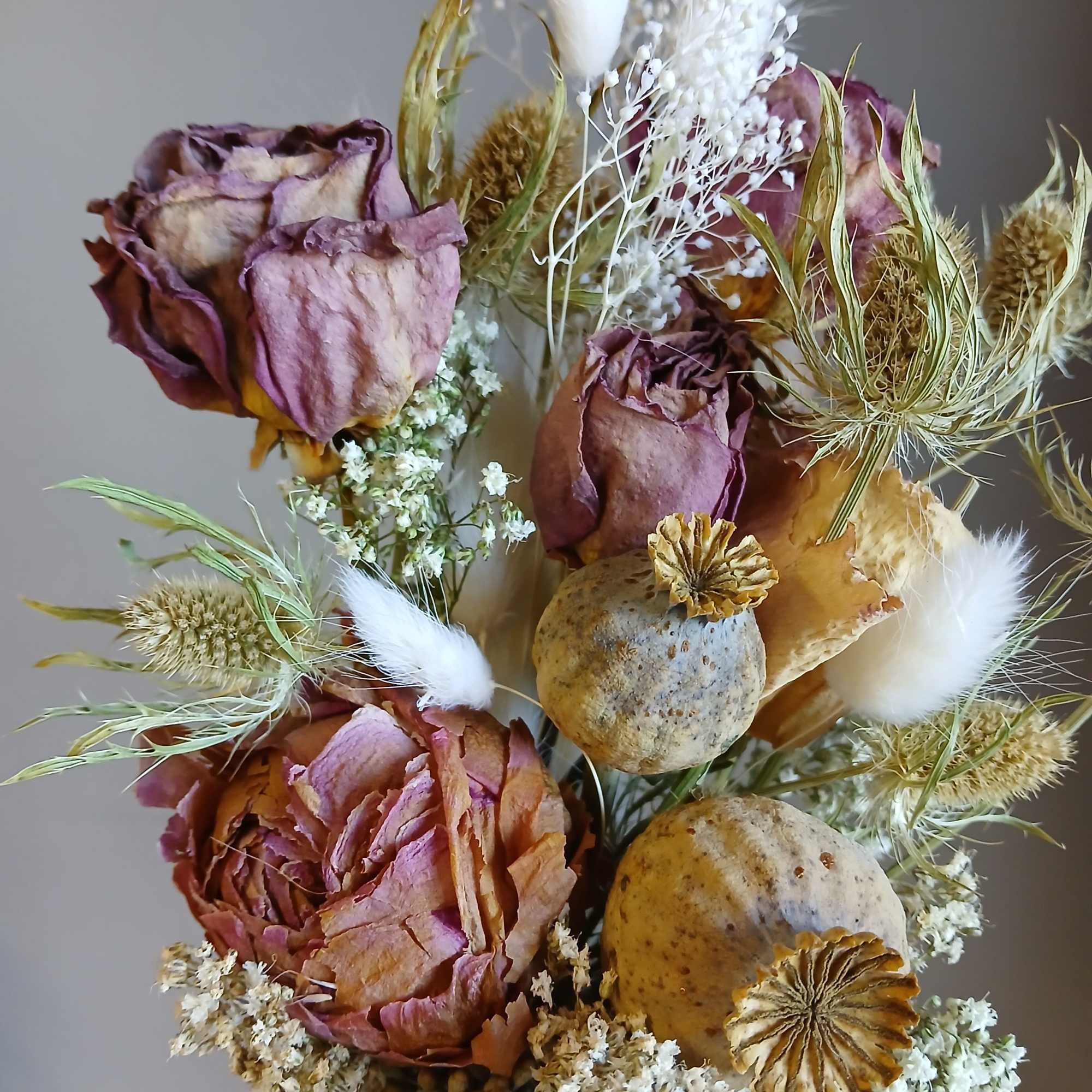 Muted pink and cream dried roses with airy white filler, seed pods
