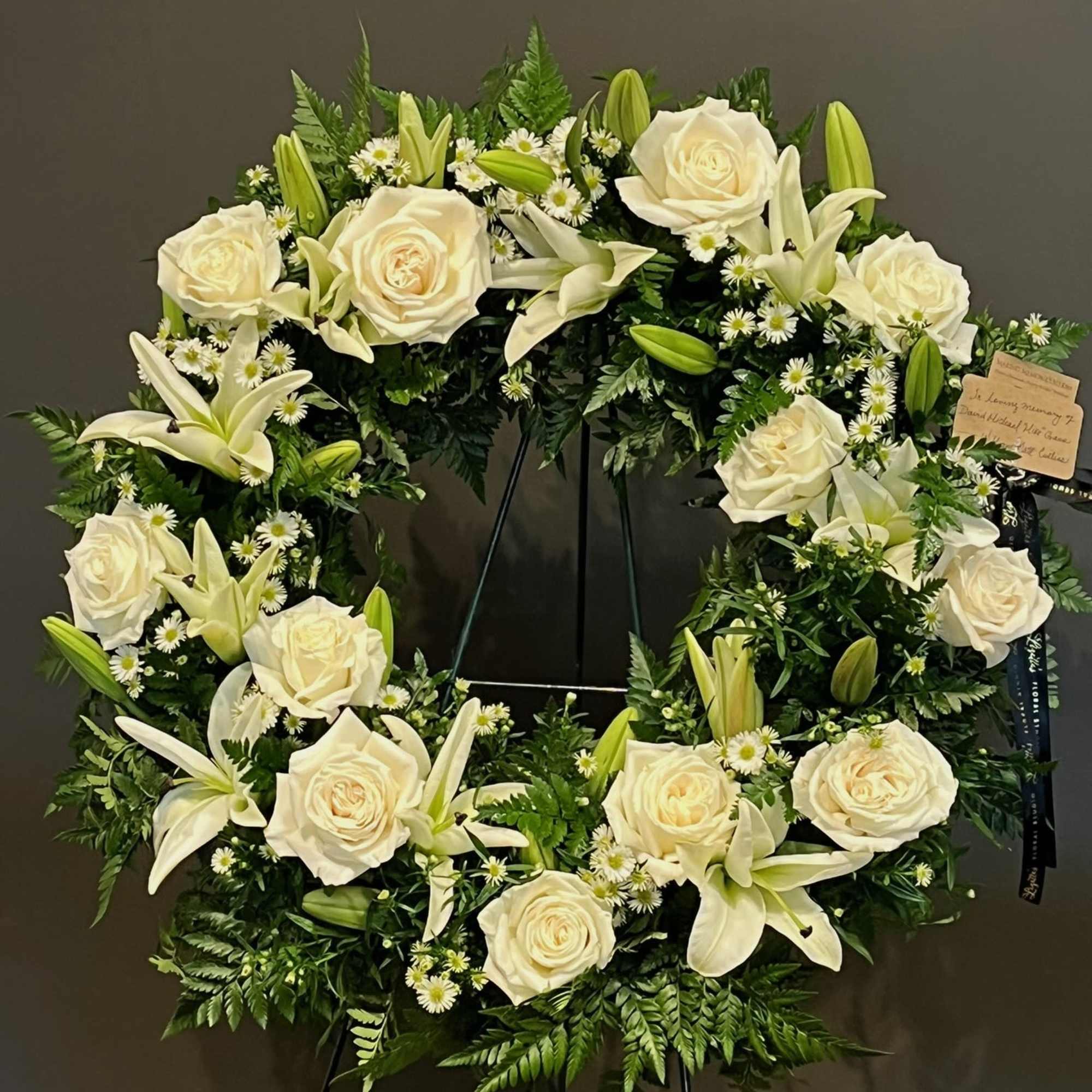 A simple and elegant sympathy wreath designed with fresh white blooms and
