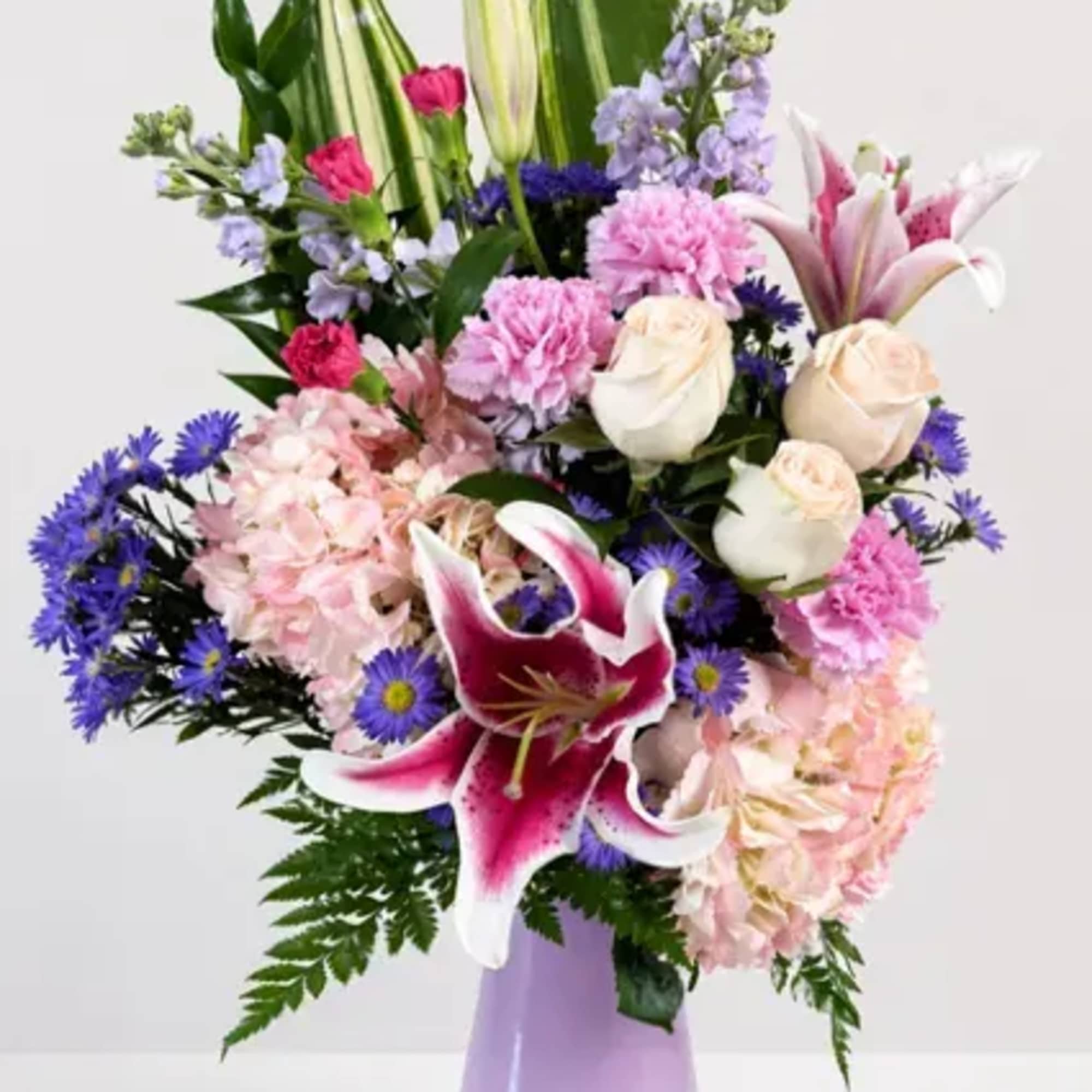 This beautiful arrangement, filled with roses, hydrangea, lilies, fillers, and greenery, is