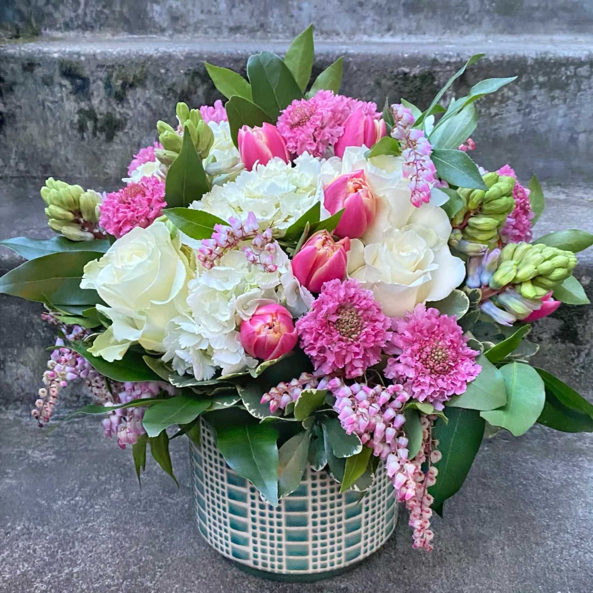 Pink and white floral arrangement in a patterned ceramic vase