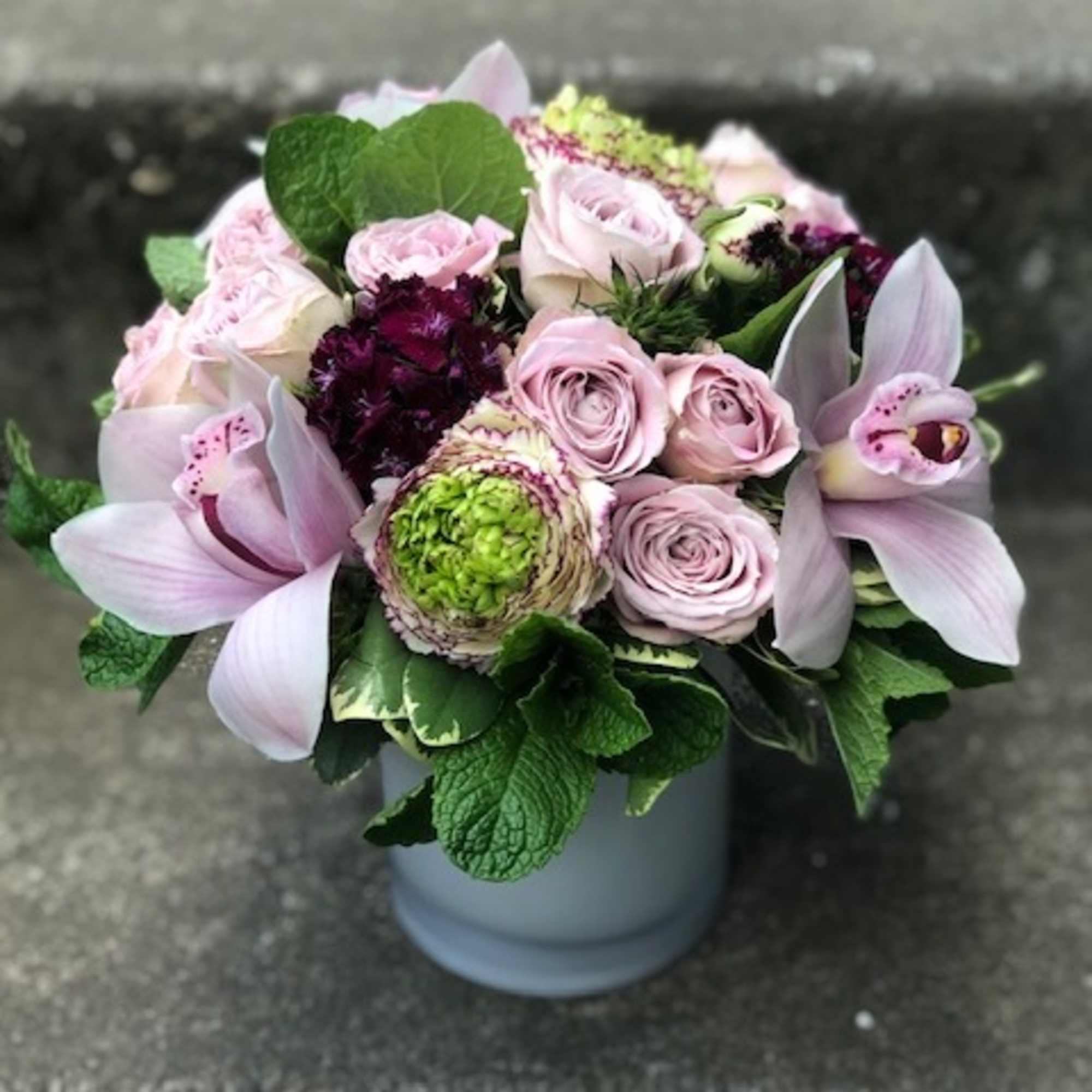 Pink roses and pale orchids arranged in a white vase