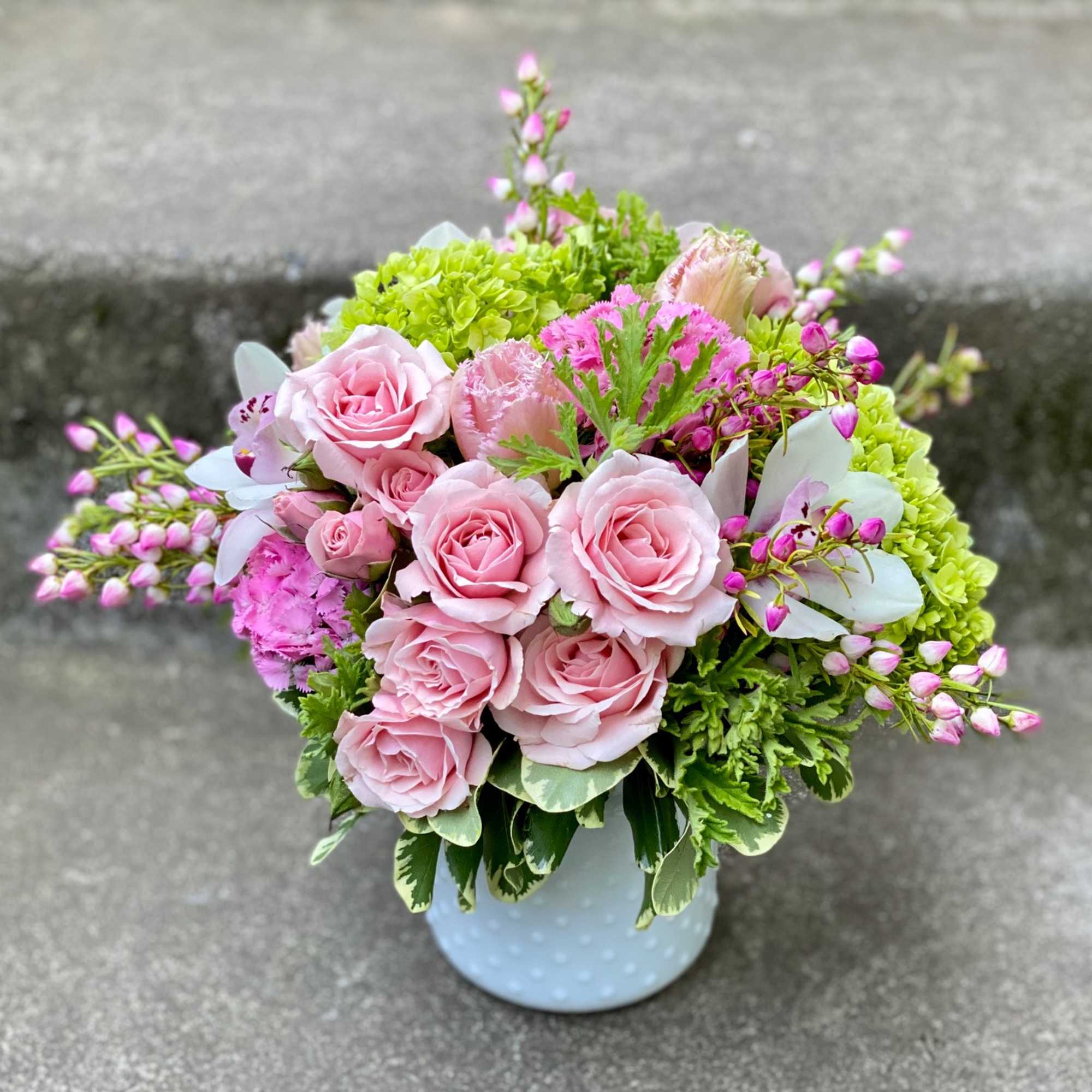 Pink roses and green blooms in a white vase