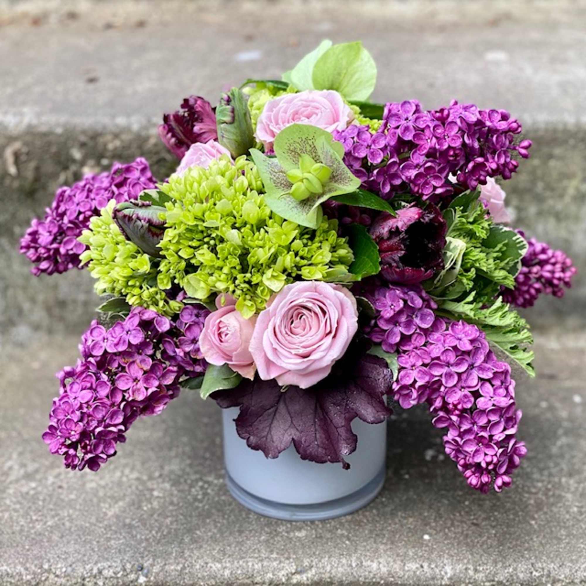 Purple and pink floral arrangement in a white vase