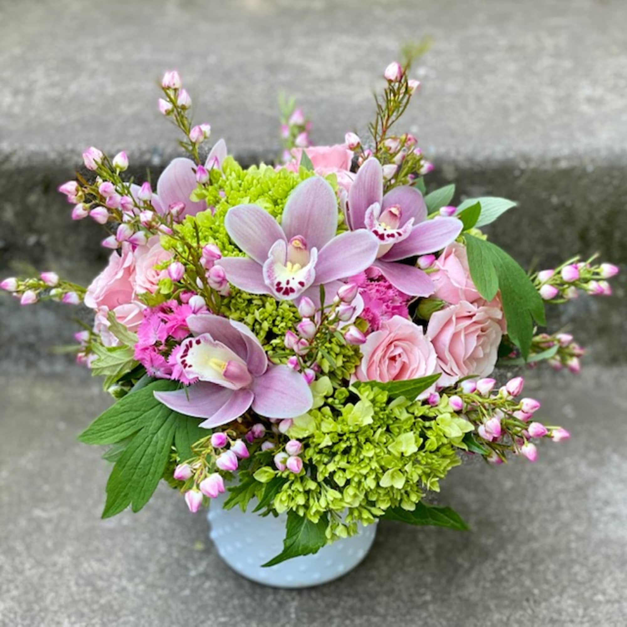 Pink orchids and roses in a white vase