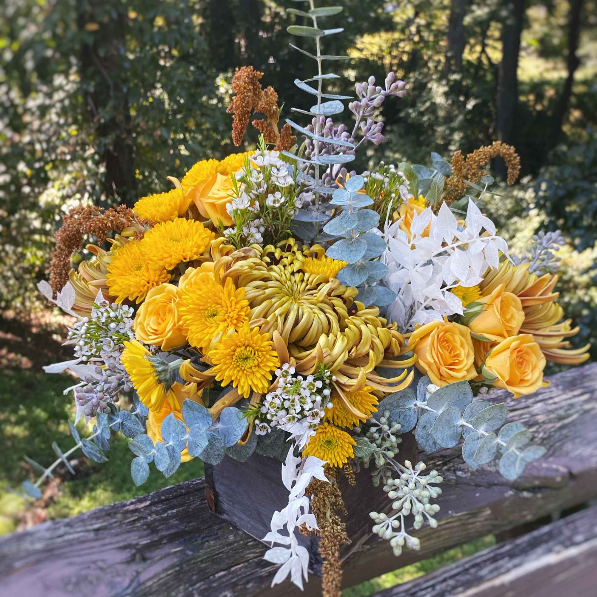 Yellow bouquet with roses and chrysanthemums in a dark box