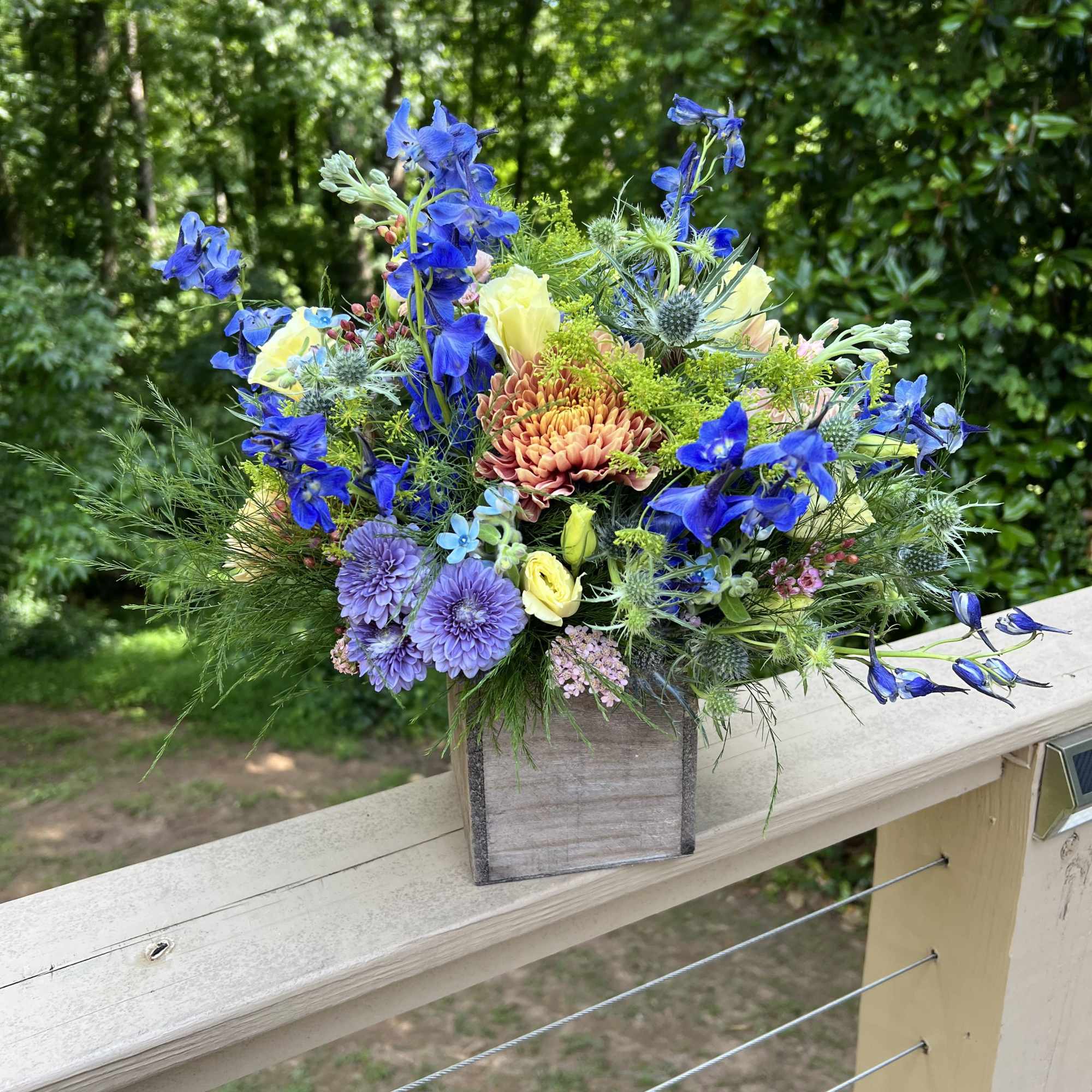 Tightly arranged flowers in a wooden box. Color palette varies throughout the