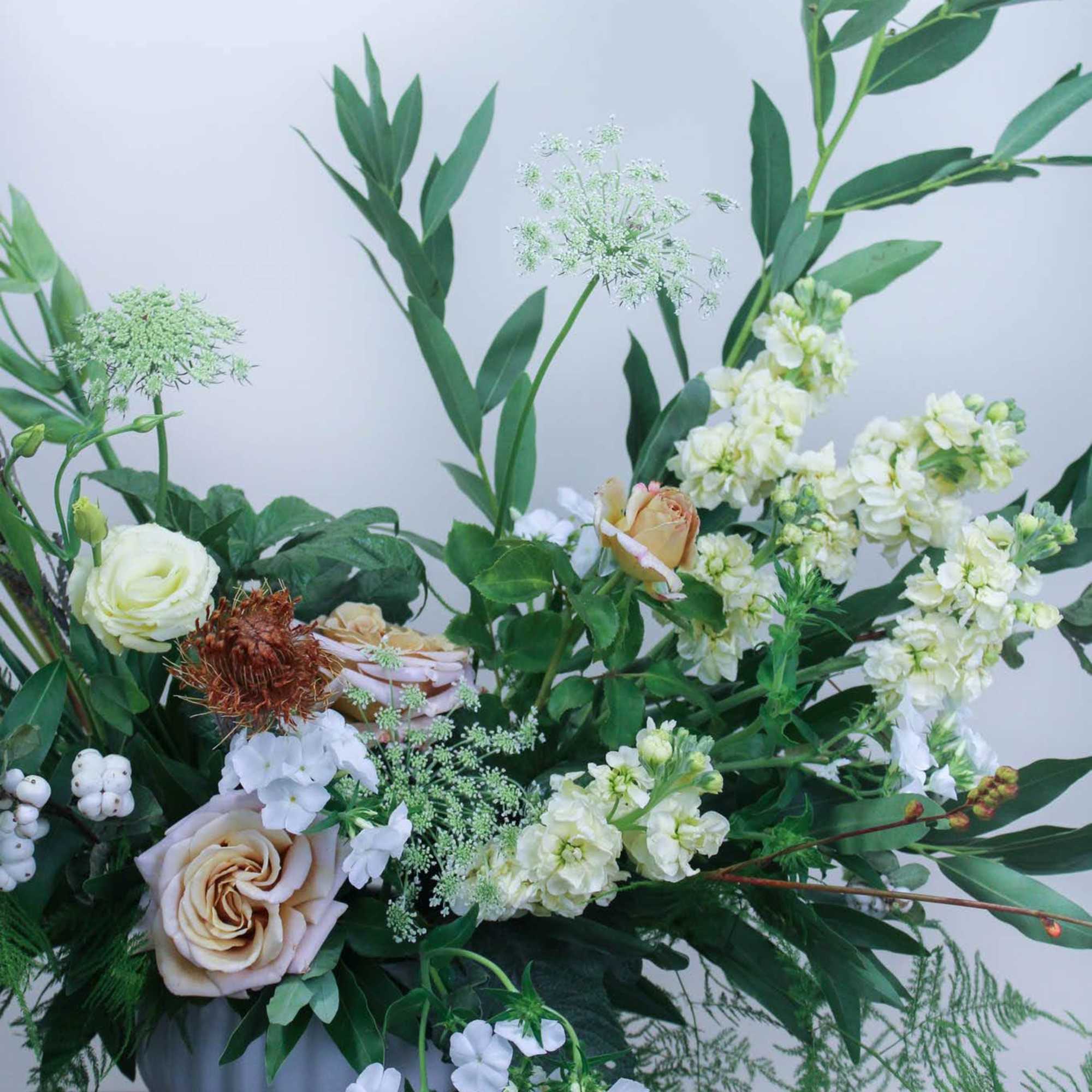 Cream and white floral arrangement in a white pedestal vase