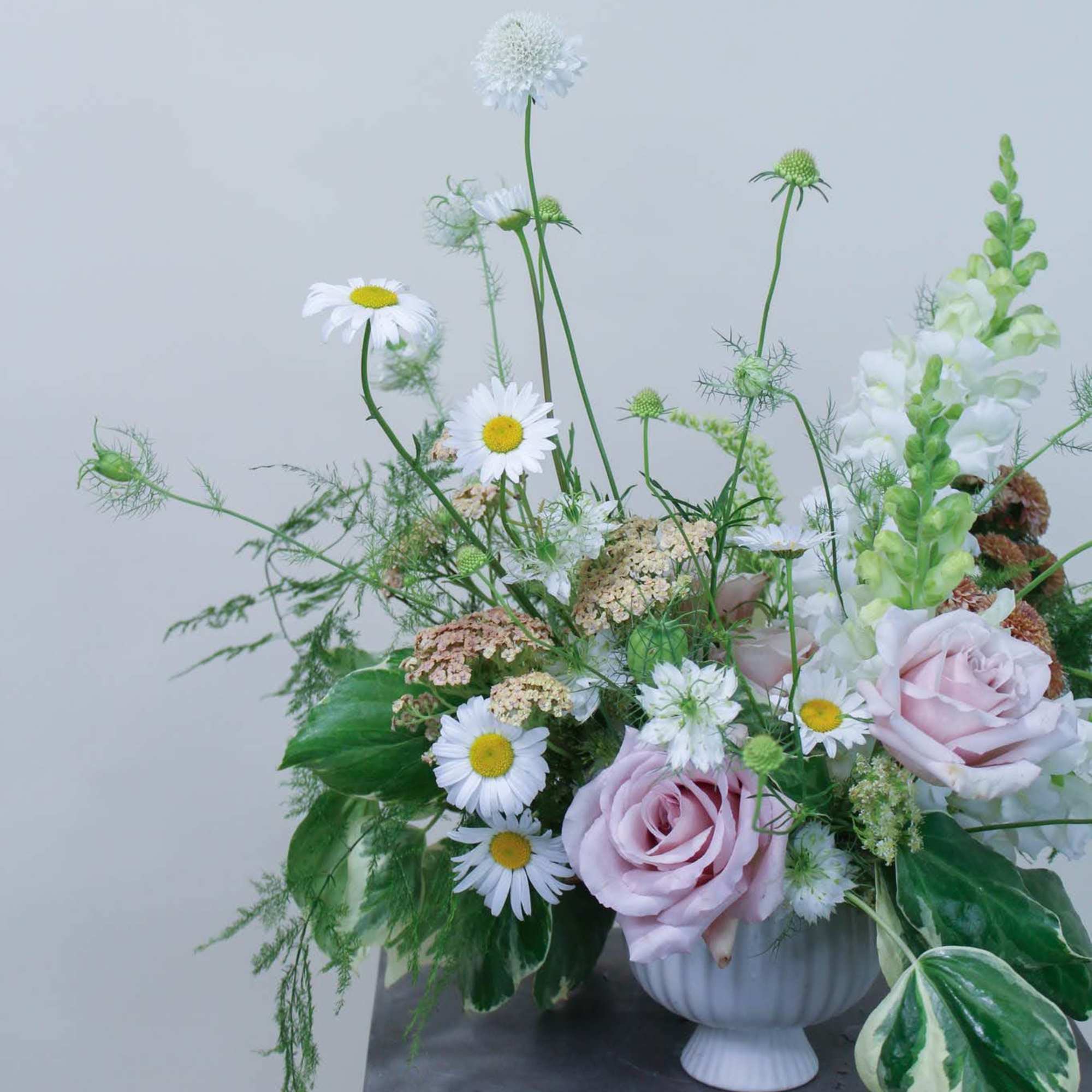 Pastel floral arrangement with pink roses and white daisies in a white vase