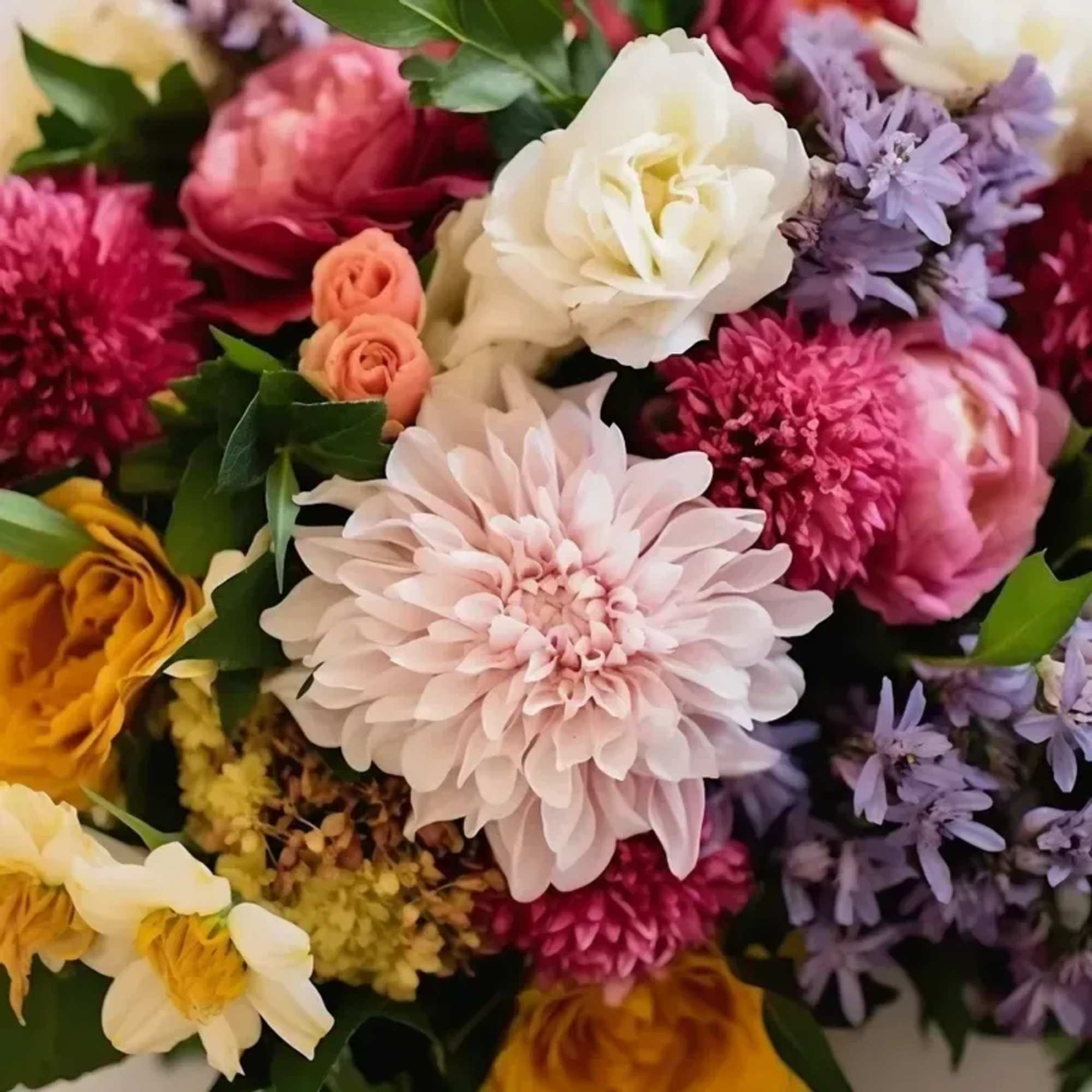 An arrangement of seasonal blooms for Birthday arranged no vase. PLEASE NOTE: