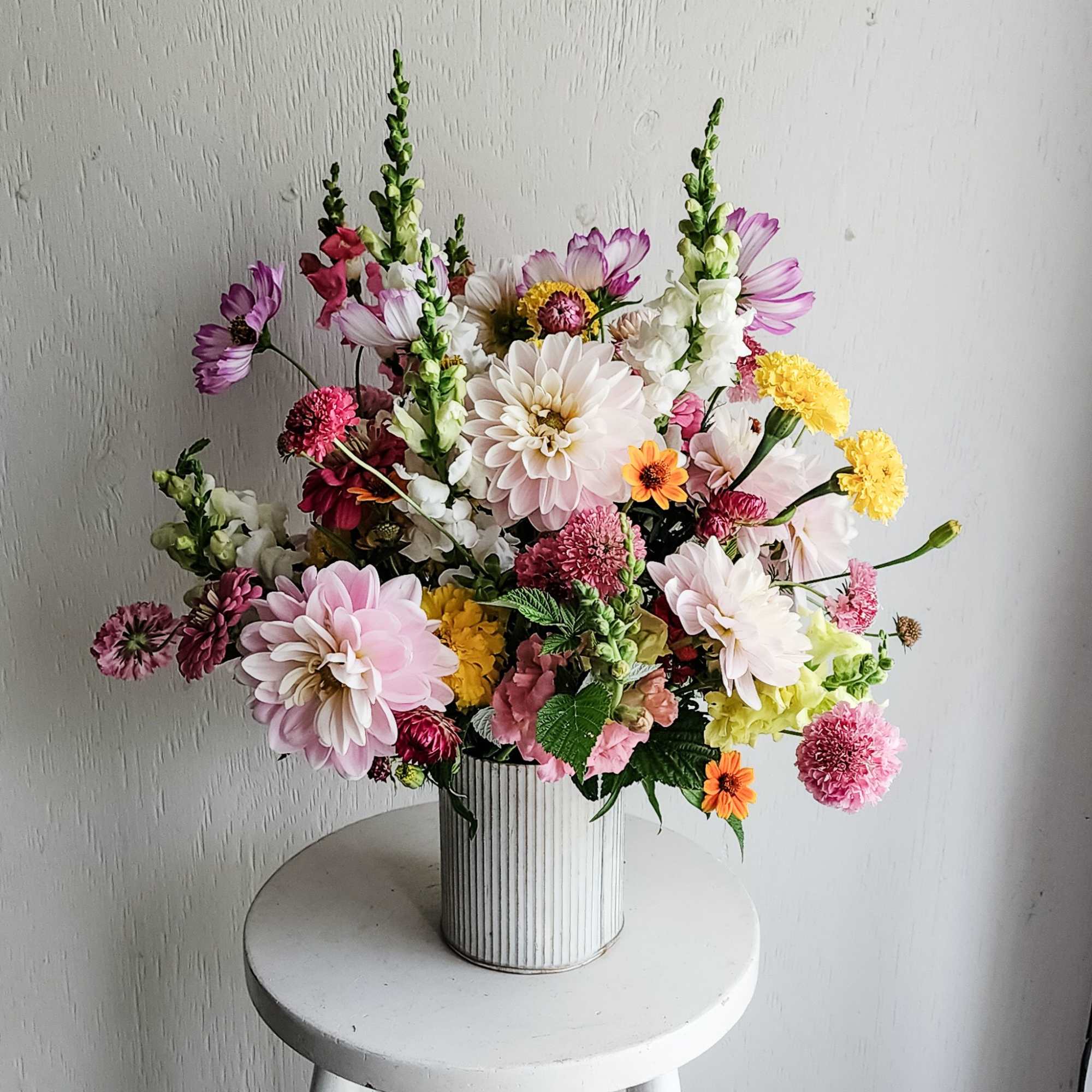 Mixed bouquet of pink, white, yellow, and purple flowers in a ribbed white vase