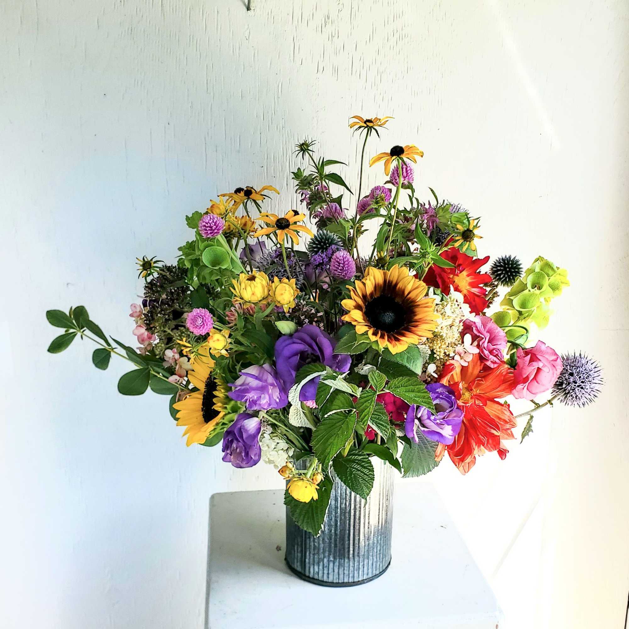 Mixed bouquet in a ribbed metal vase with sunflowers and purple blooms