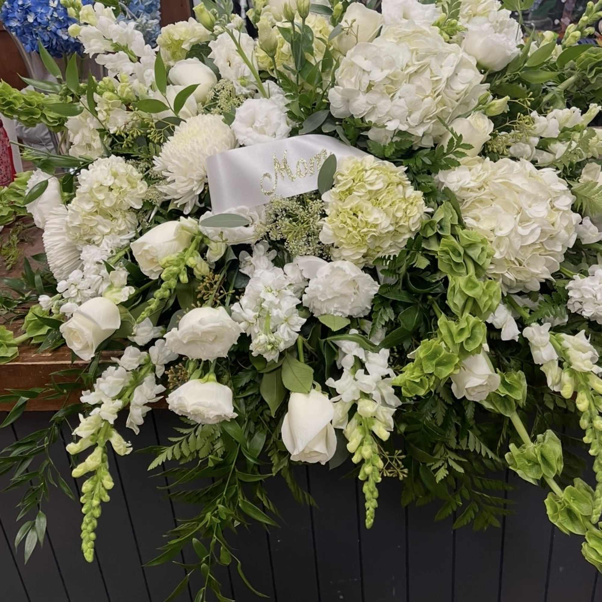 A sweeping, low casket cover in serene white and fresh green makes