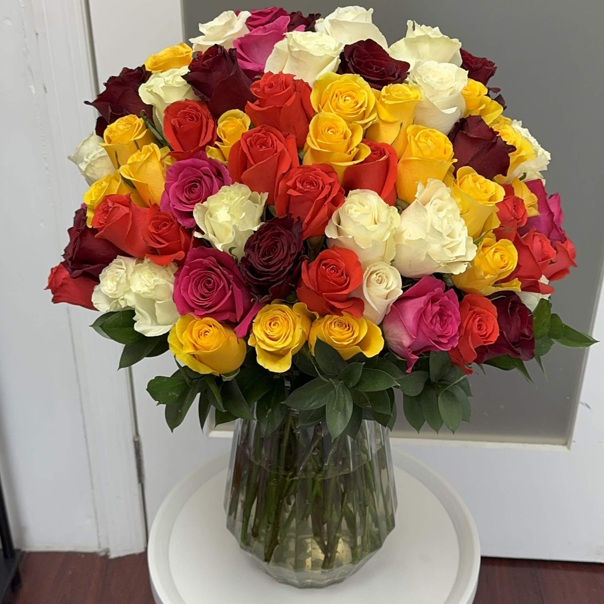 Large bouquet of multicolored roses in a clear glass vase