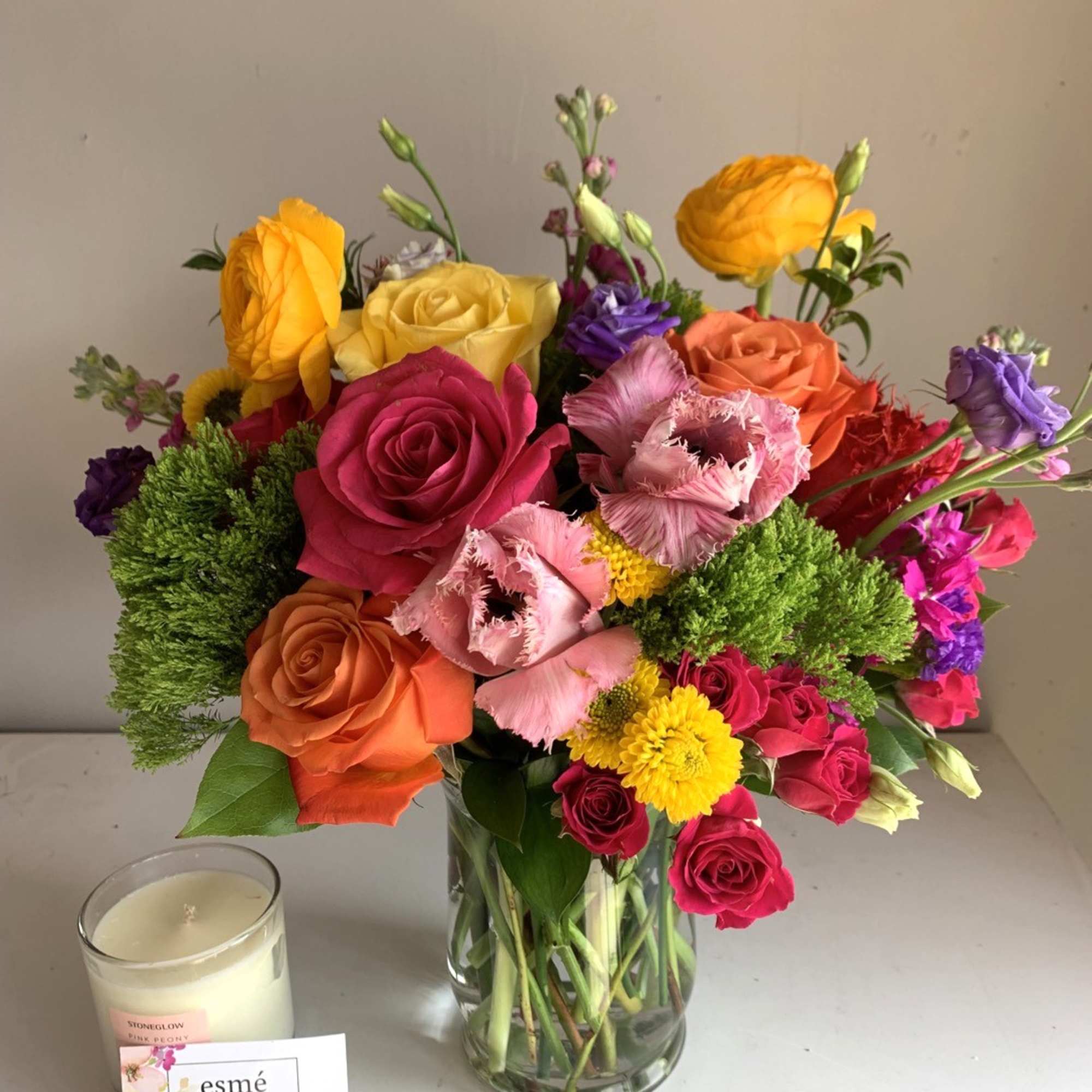 Colorful mixed bouquet of roses and other flowers in a glass vase