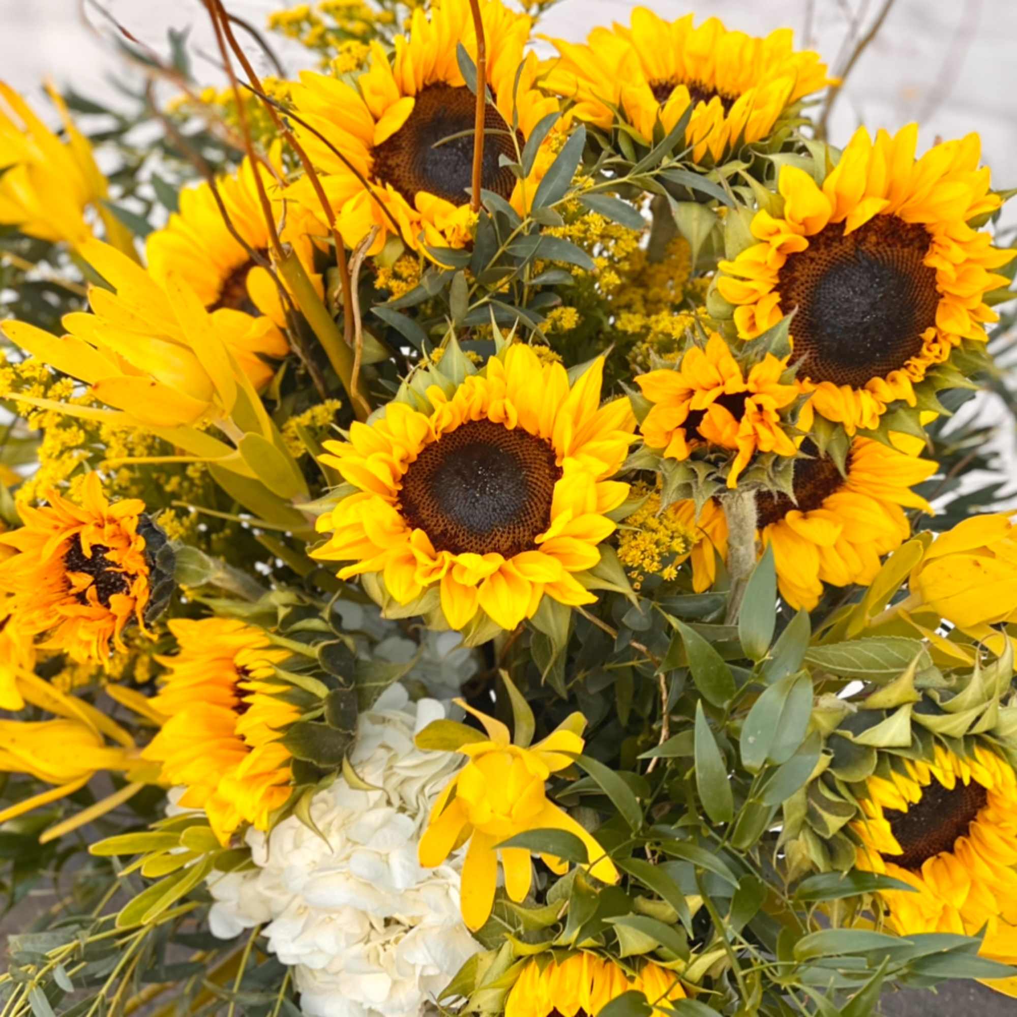 Bouquet of yellow sunflowers with white blooms and greenery
