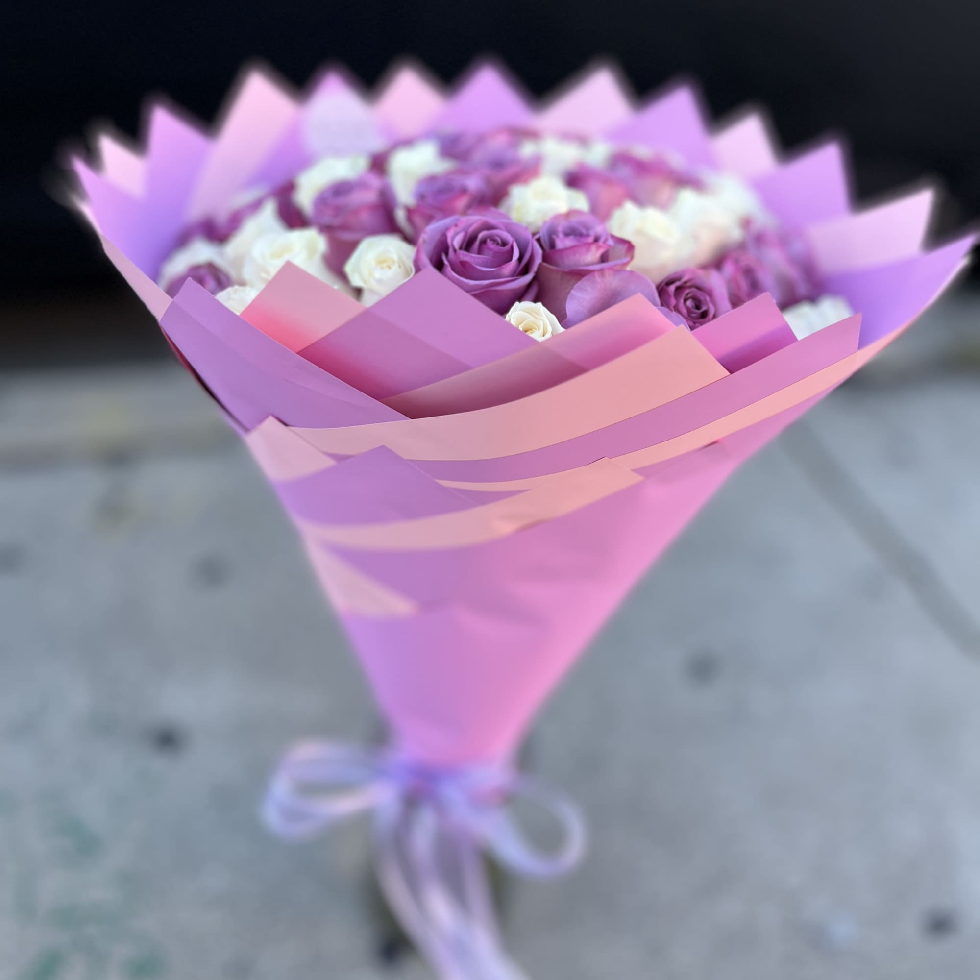 Bouquet of purple and white roses wrapped in pink paper