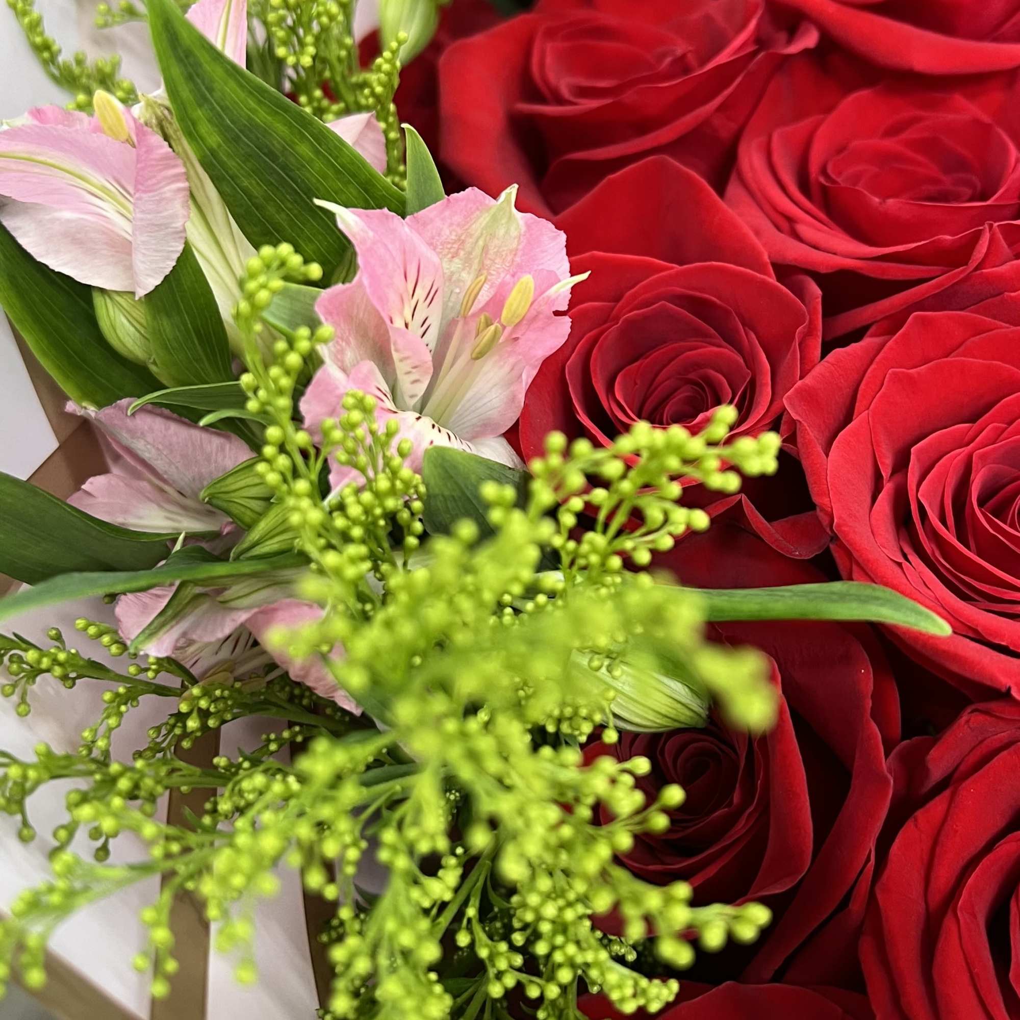 Bouquet of red roses and pink lilies with bright green filler