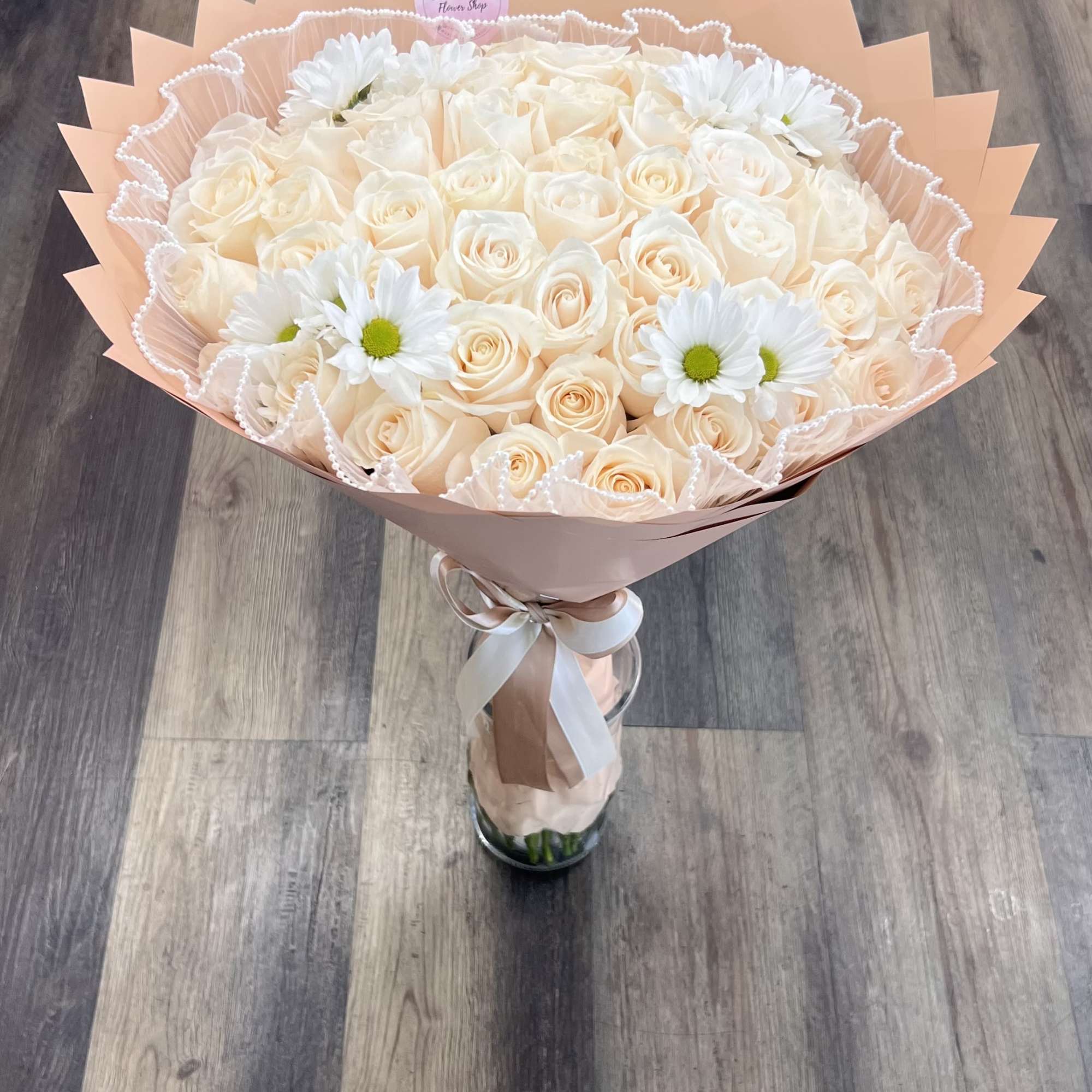 &ldquo;A timeless bouquet of creamy ivory roses accented with fresh white daisies.