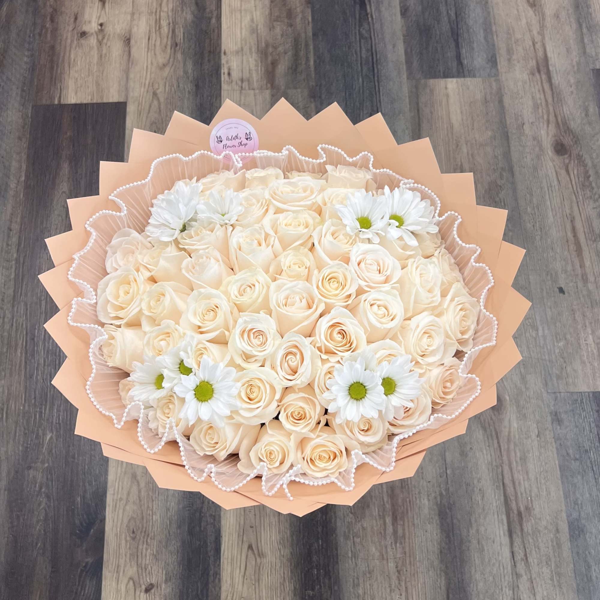 &ldquo;A timeless bouquet of creamy ivory roses accented with fresh white daisies.