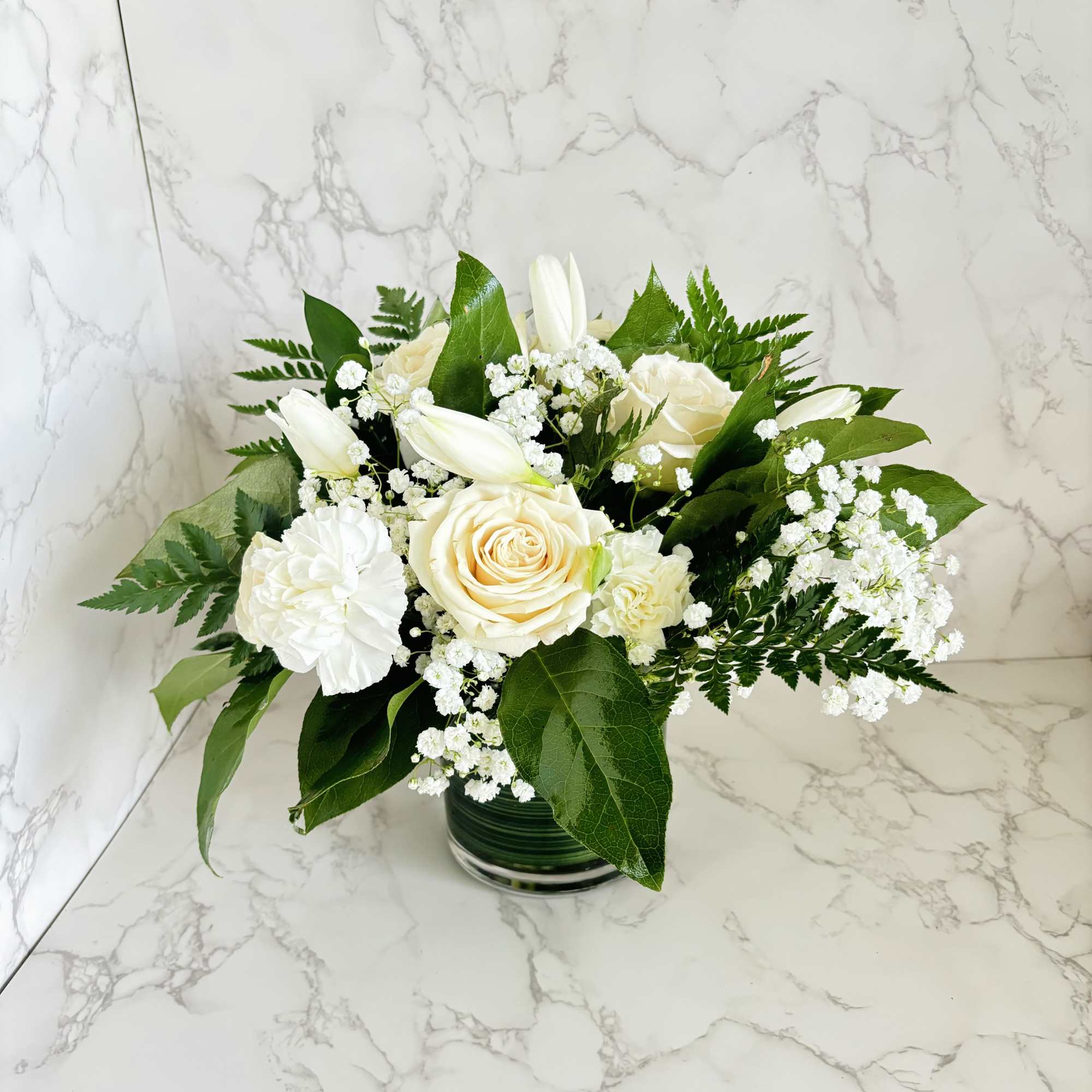 White roses and lilies arranged in a glass vase