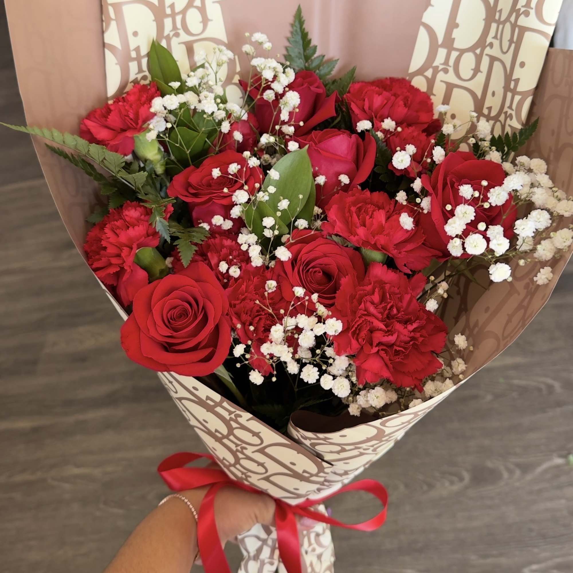 Bouquet of red roses and carnations with white baby's breath in patterned wrap