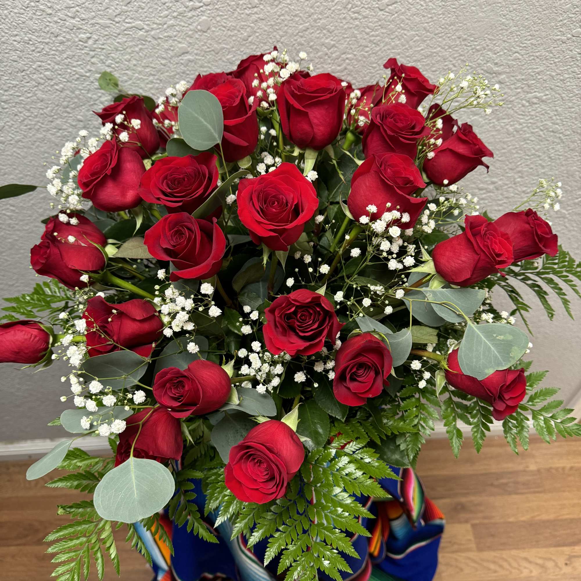 Beautiful dozen roses accompanied by Baby Breaths, Fern, and Eucalyptus in a