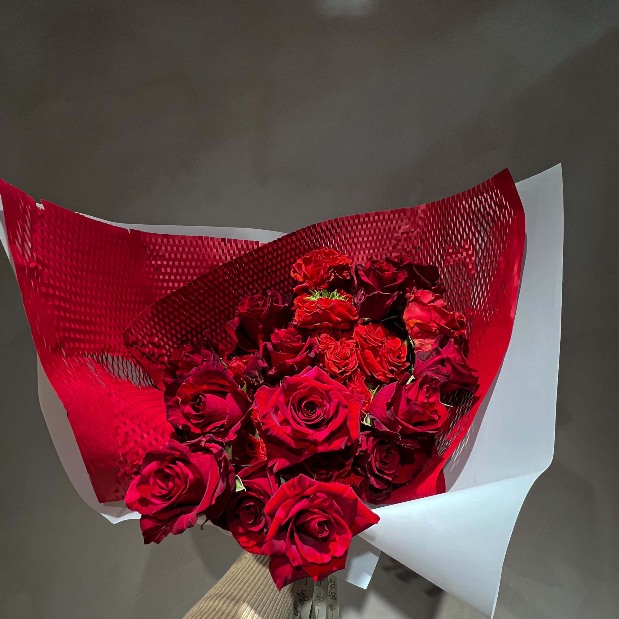 Bouquet of red roses wrapped in red and white paper