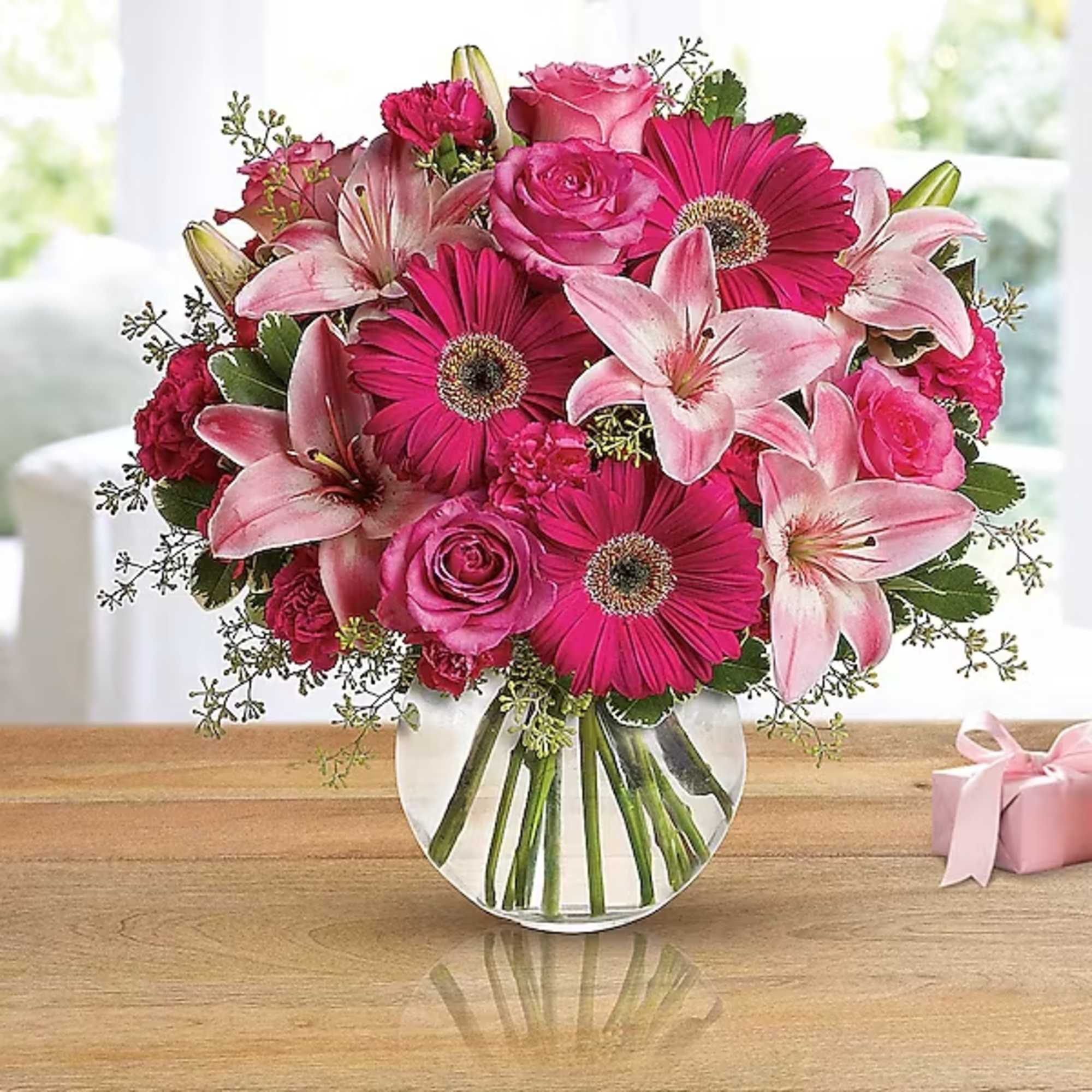 Pink bouquet of roses, lilies, and gerbera daisies in a glass vase